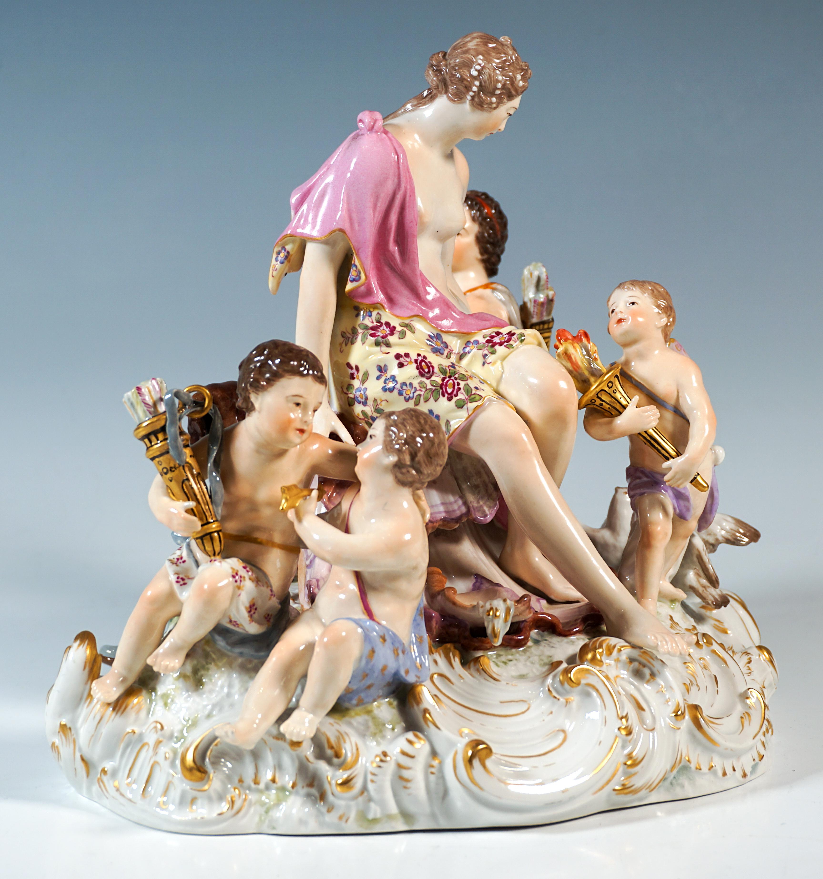 Excellent groupe de porcelaine KPM du début du 20e siècle :
Assise au centre sur un piédestal en coquillage surélevé, la jeune et belle Diane, les cheveux noués sur la nuque et ornés de perles, sa nudité partiellement couverte par un tissu noué sur