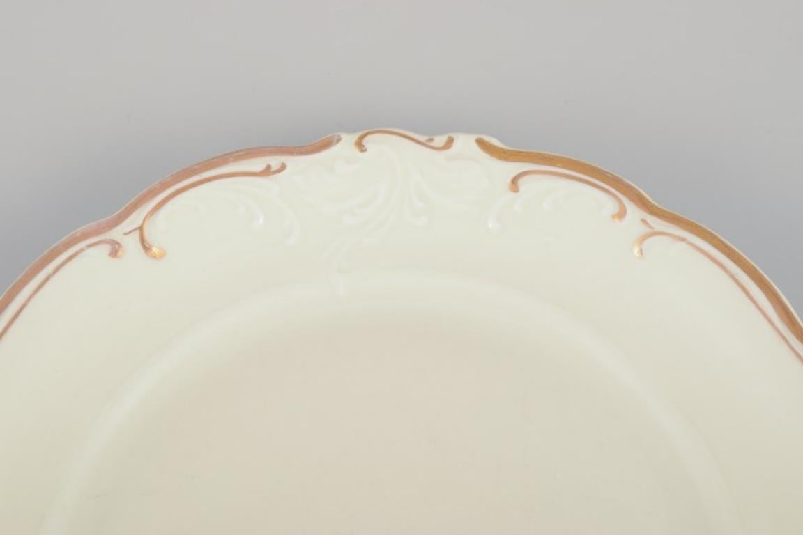 KPM, Polen. Set von neun cremefarbenen, cremefarbenen Porzellantellern mit Golddekoration. (Polnisch) im Angebot