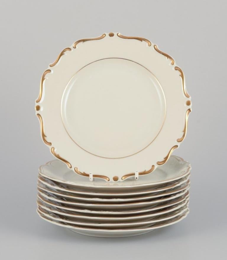 KPM, Poland. Set of nine cream-colored porcelain plates with gold decoration.  For Sale