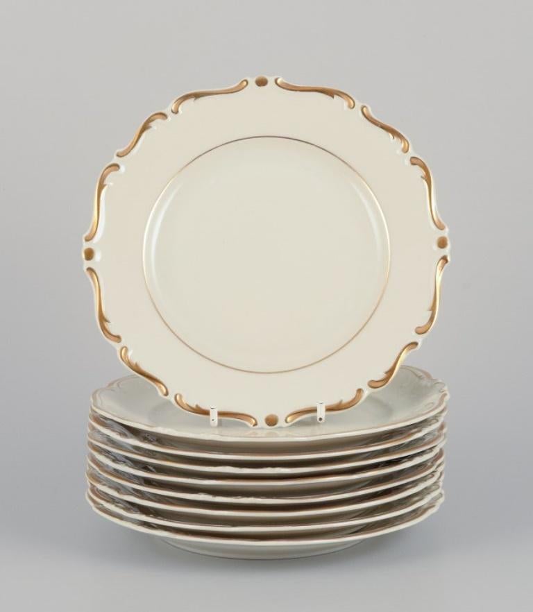 KPM, Polonia. Juego de nueve platos de porcelana color crema con decoración dorada.
