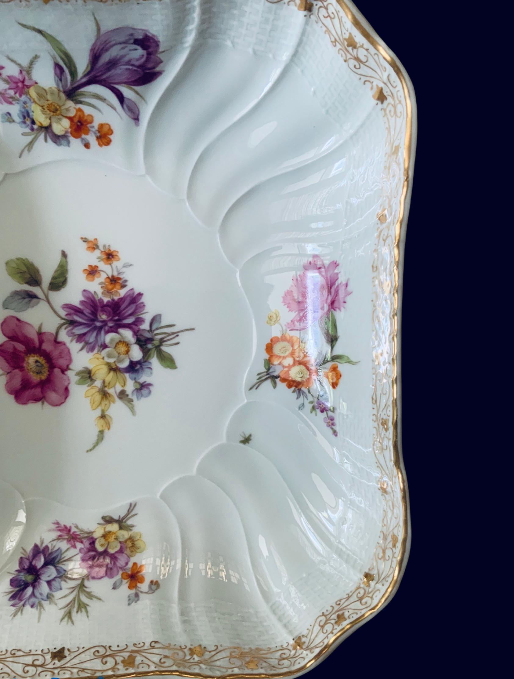 This is a KPM Porcelain large octagonal bowl. It depicts a large bouquet of flowers in the center and four small ones around the border. A delicate gilt vine of hearts and ivy leaves embellish the border in addition of the spiral and basket weave