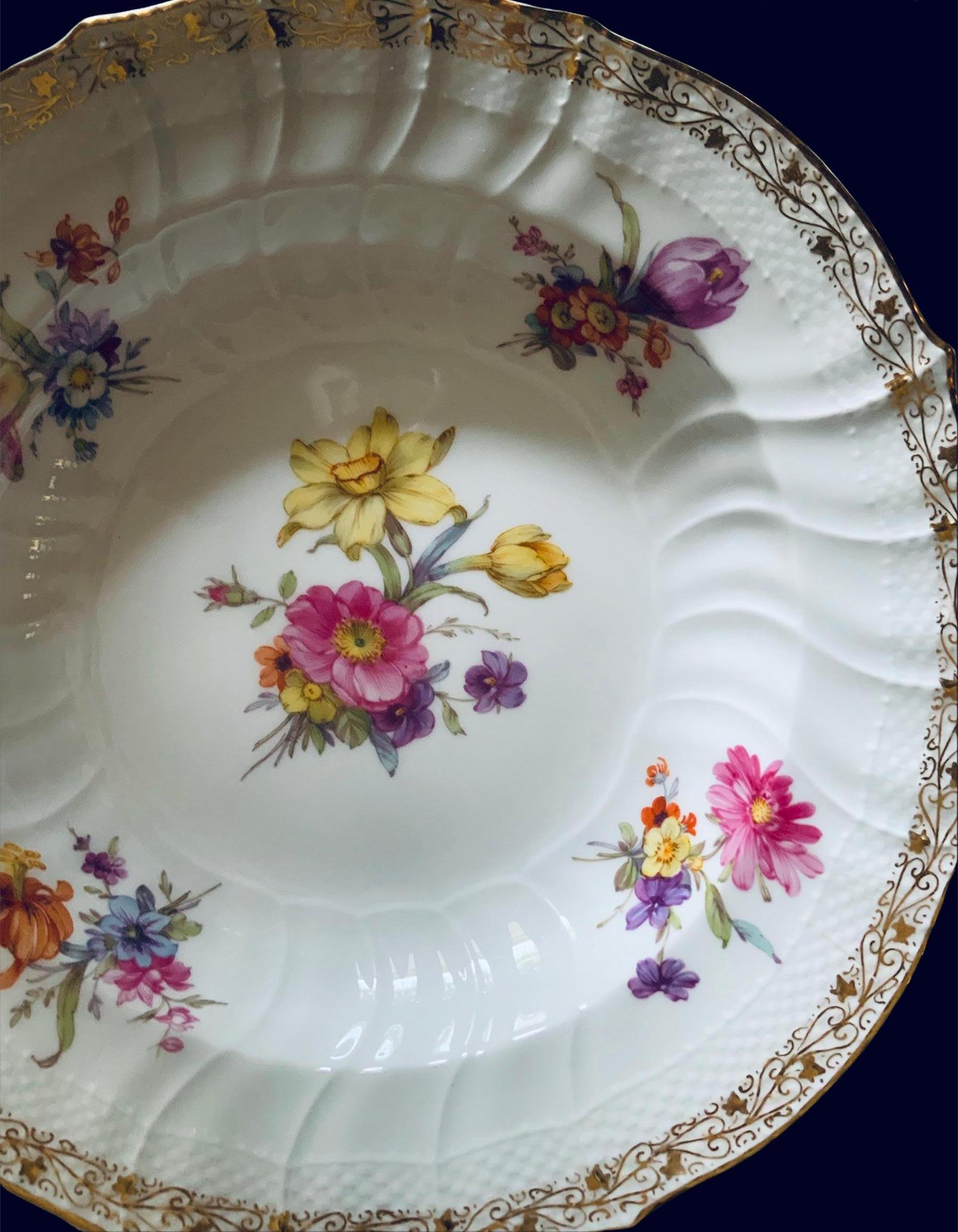 This is a KPM Porcelain set of two large bowl plates. They are decorated with a large bouquet of flowers in the center and four small bouquets of flowers around the border. A delicate gilt vine of hearts and ivy leaves embellish the border in