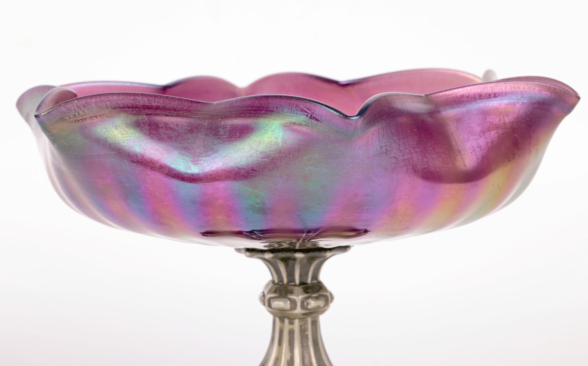 A stylish Czech/Bohemian Art Nouveau pedestal iridescent purple glass bowl attributed to renowned makers Kralik and dating from around 1904. The bowl is hand blown in wide rounded shaped with a pinched and floral shaped rim with ribbing extending