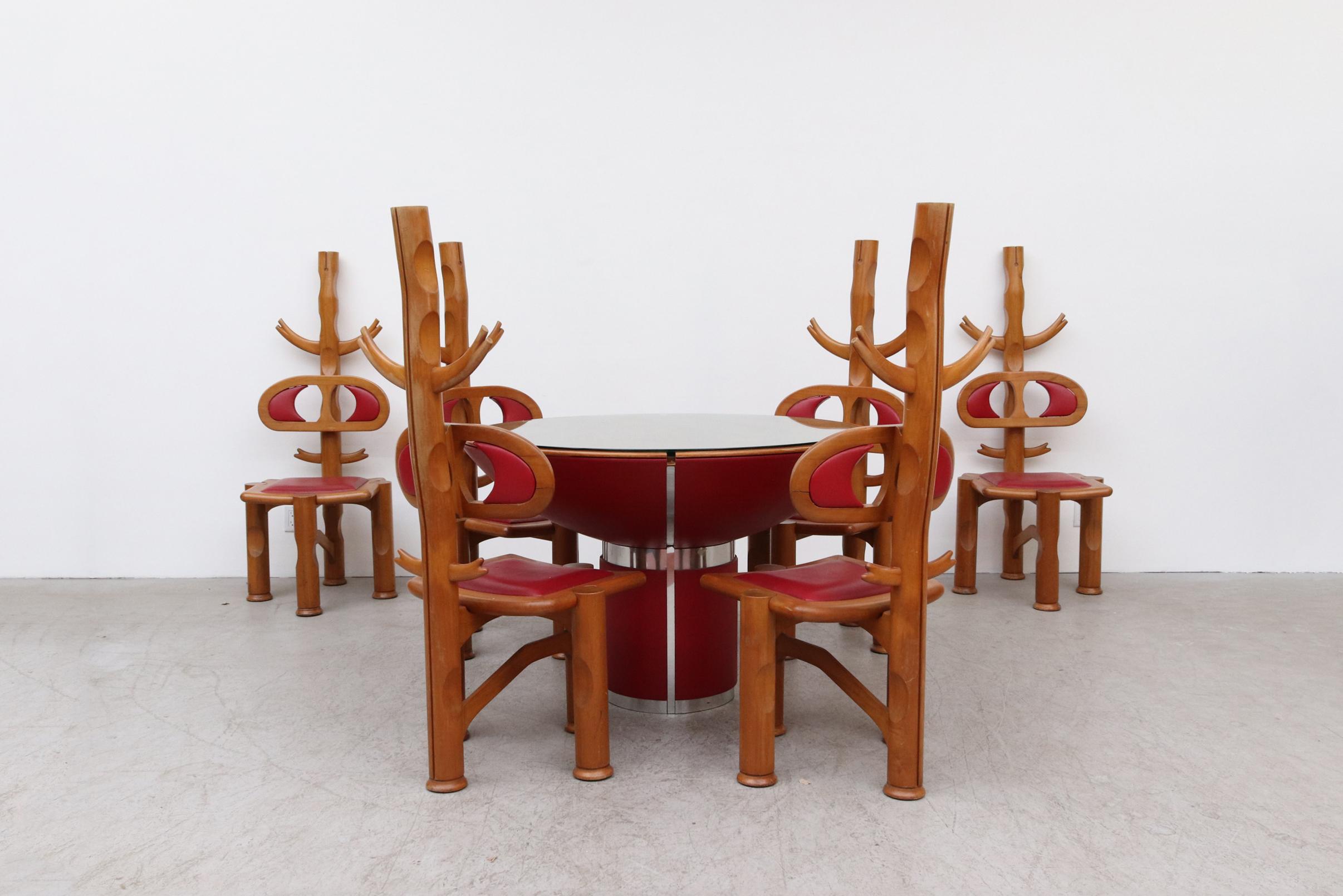 Insanely conceived and executed 1980's Italian carved elm table and 6 chair set. The drum shaped table and pedestal base is wrapped in red leather with Chrome Trim. The concave top is lined with inlaid wood and topped with a thick inset glass plate.