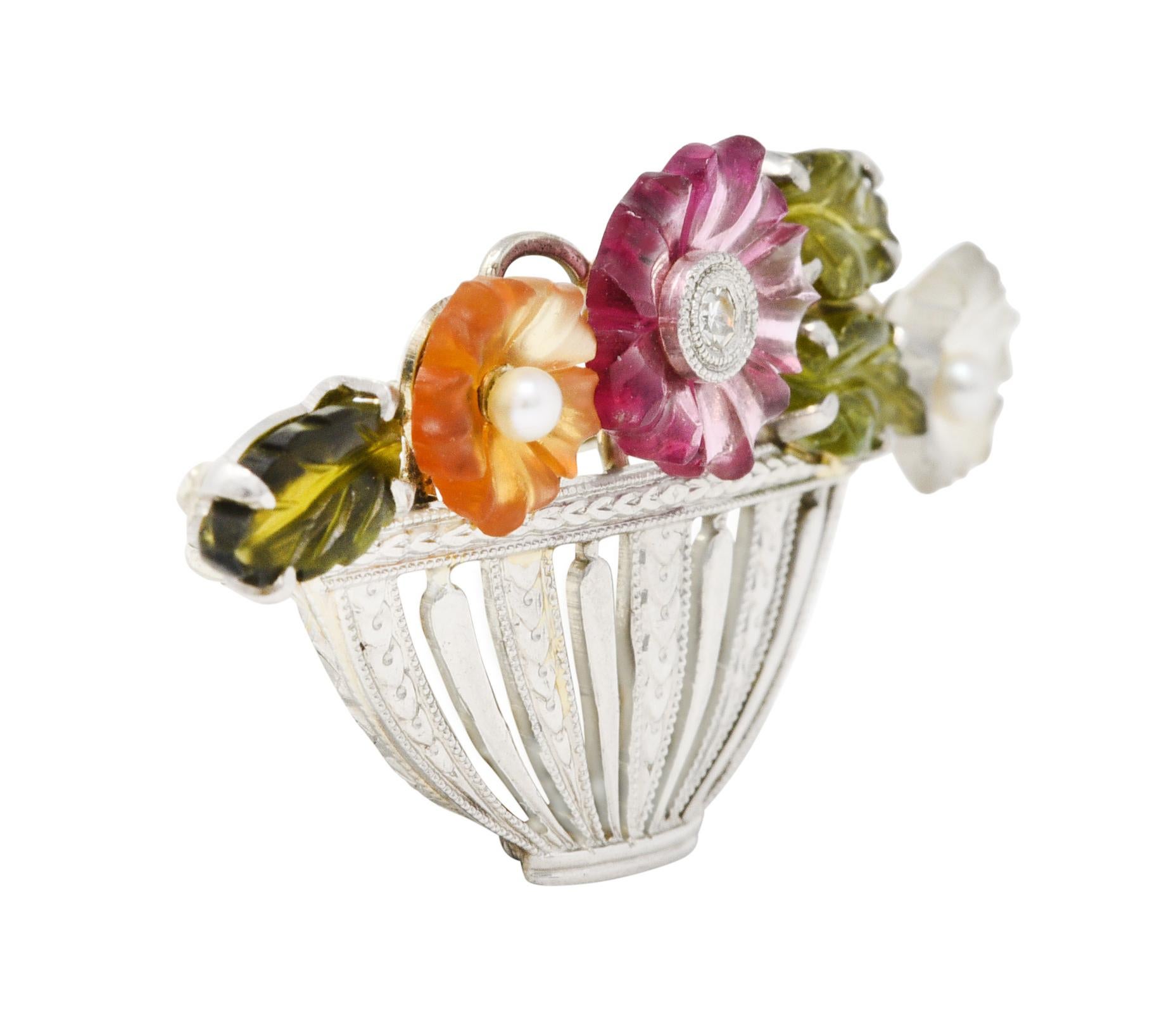 Giardinetto brooch is designed as a pierced bowl-like vase full of carved gemstone florals

Bowl is pierced and striated with a hand engraved wheat motif

With carved tourmaline leaves - very well matched olive green in color

Centering a purplish
