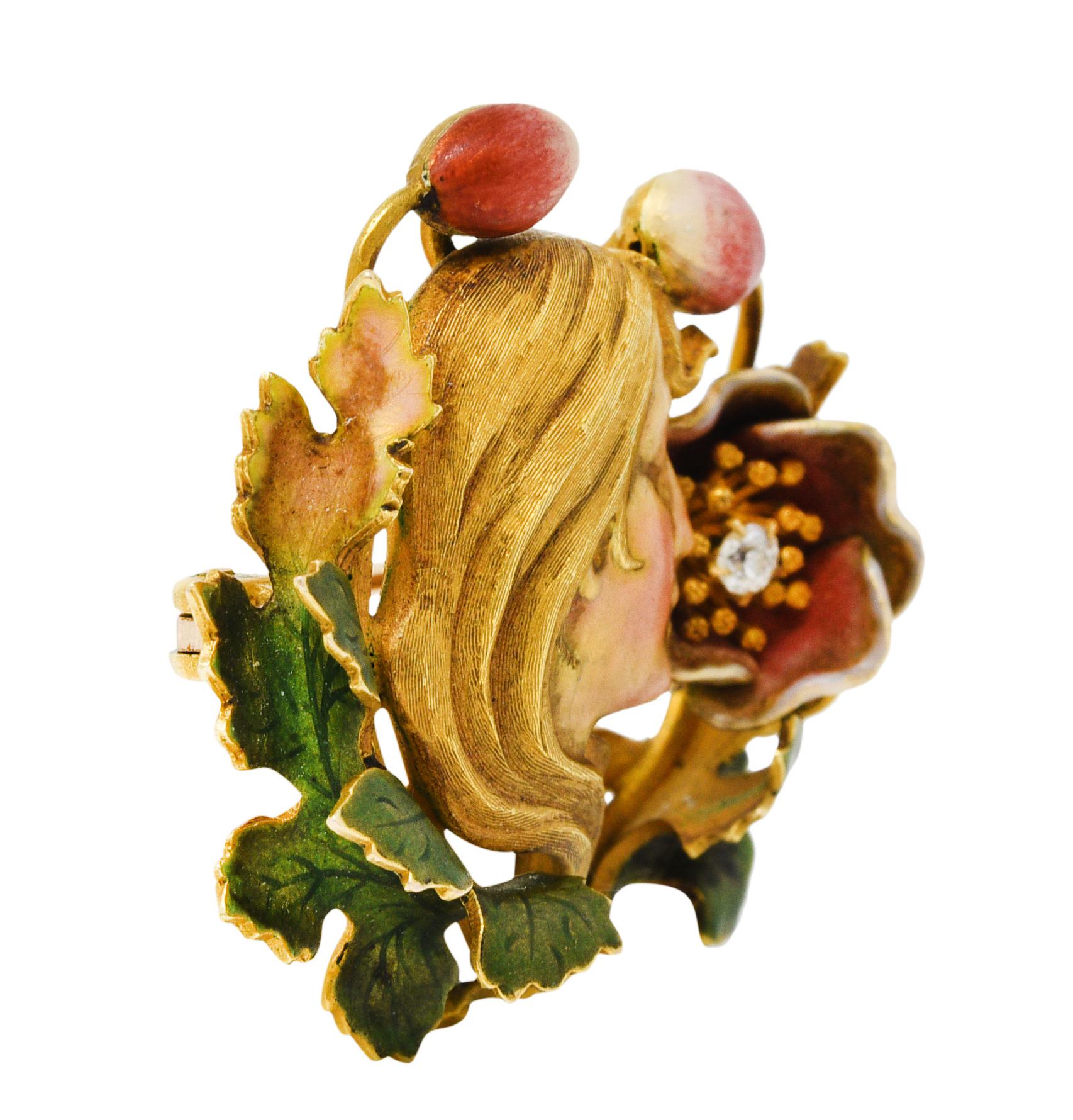 Highly dimensional brooch depicts a woman smelling a blooming flower

Woman features a highly rendered profile with textured windswept hair

Face is glossed with iridescent enamel - blushed at cheeks

Florals and foliate are colored by matte enamel