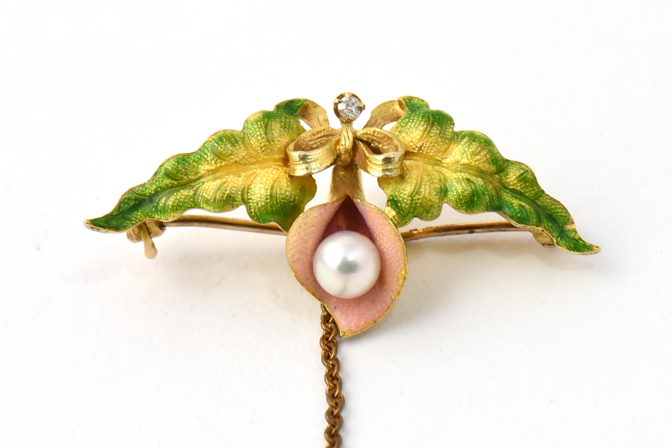 Krementz Art Nouveau enamel, pearl, and diamond two-piece brooch. Features a flower holding a pearl inside with a diamond-studded bow at the stem and two gold and green enamel leaves that almost look like wings. The bottom brooch has two matching