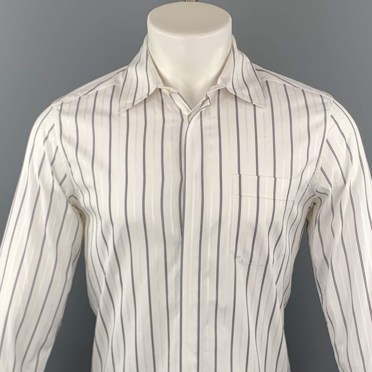 KRIS VAN ASSCHE long sleeve shirt comes in a white and navy striped cotton featuring a button up style, hidden button closure, spread collar, and a front patch pocket. Made in Italy.

Excellent Pre-Owned Condition.
Marked: IT