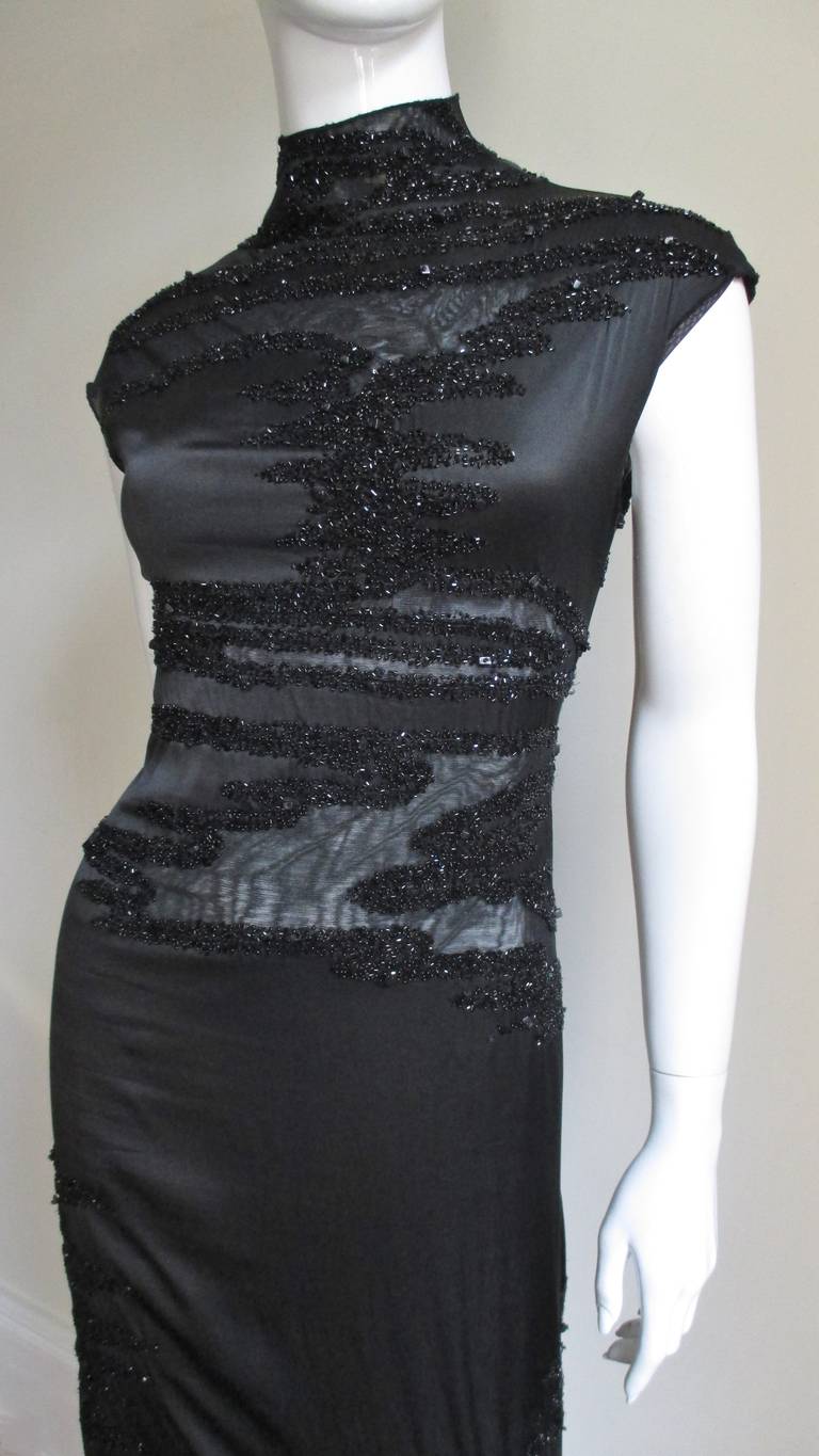 A stunning Krizia black fine stretch silk dress with abstract shaped semi sheer insets outlined with black glass beads.  It has a stand up collar, cap sleeves, full lining and slips on over the head.   
Fits size Extra Small, Small, Medium. Marked