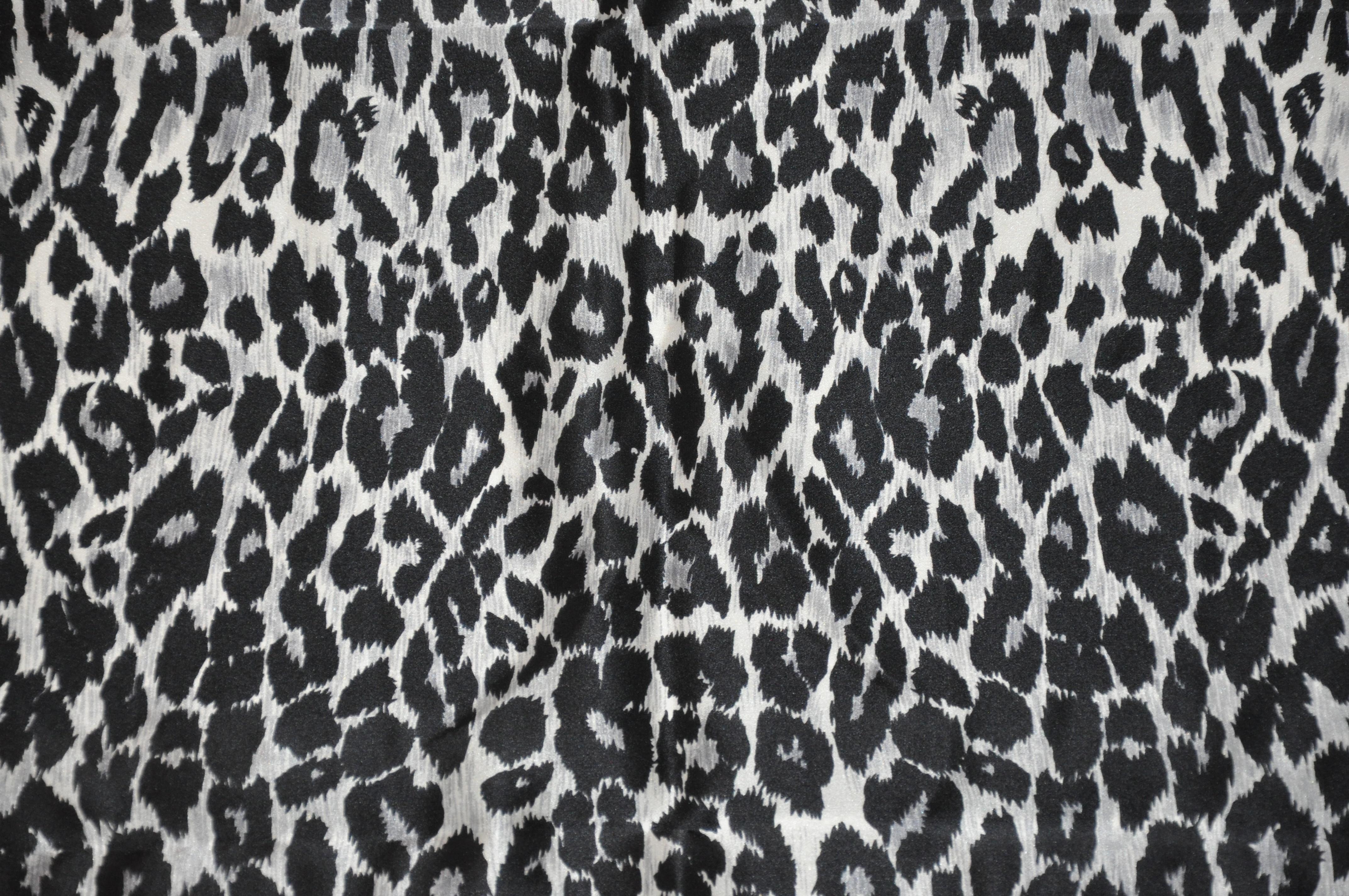        L'écharpe Krizia en soie à imprimé léopard majestueux noir et gris acier, merveilleusement détaillée, est agrémentée de bords roulés à la main et mesure 34 pouces sur 34 pouces. Fabriquées en Italie.