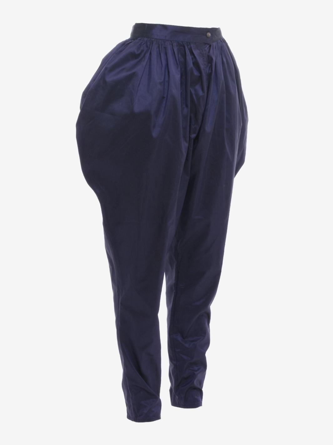 Le pantalon Ballon de soie de Krizia est un pantalon de style indien probablement fabriqué à la fin des années 1970. Le vêtement est doté d'une taille haute boutonnée, de poches latérales et d'une coupe douce et fraîche grâce notamment au tissu de