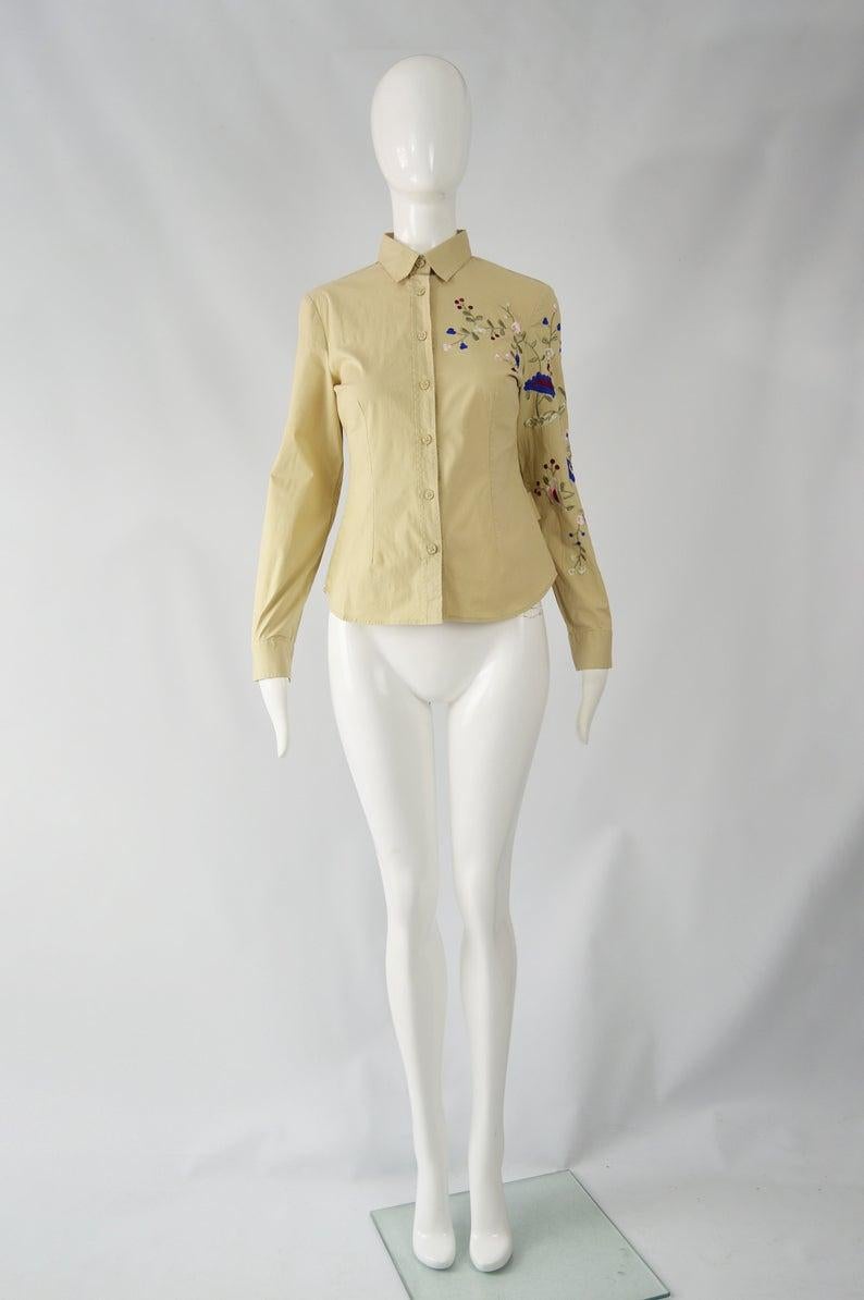 Preciosa camisa vintage Krizia para mujer en color caqui con un bordado ornamentado en uno de los lados, que añade un toque bohemio a una blusa que, de otro modo, sería minimalista. 

Talla: se ajusta como una mujer moderna UK 10/ US 6/ EU 38. Por
