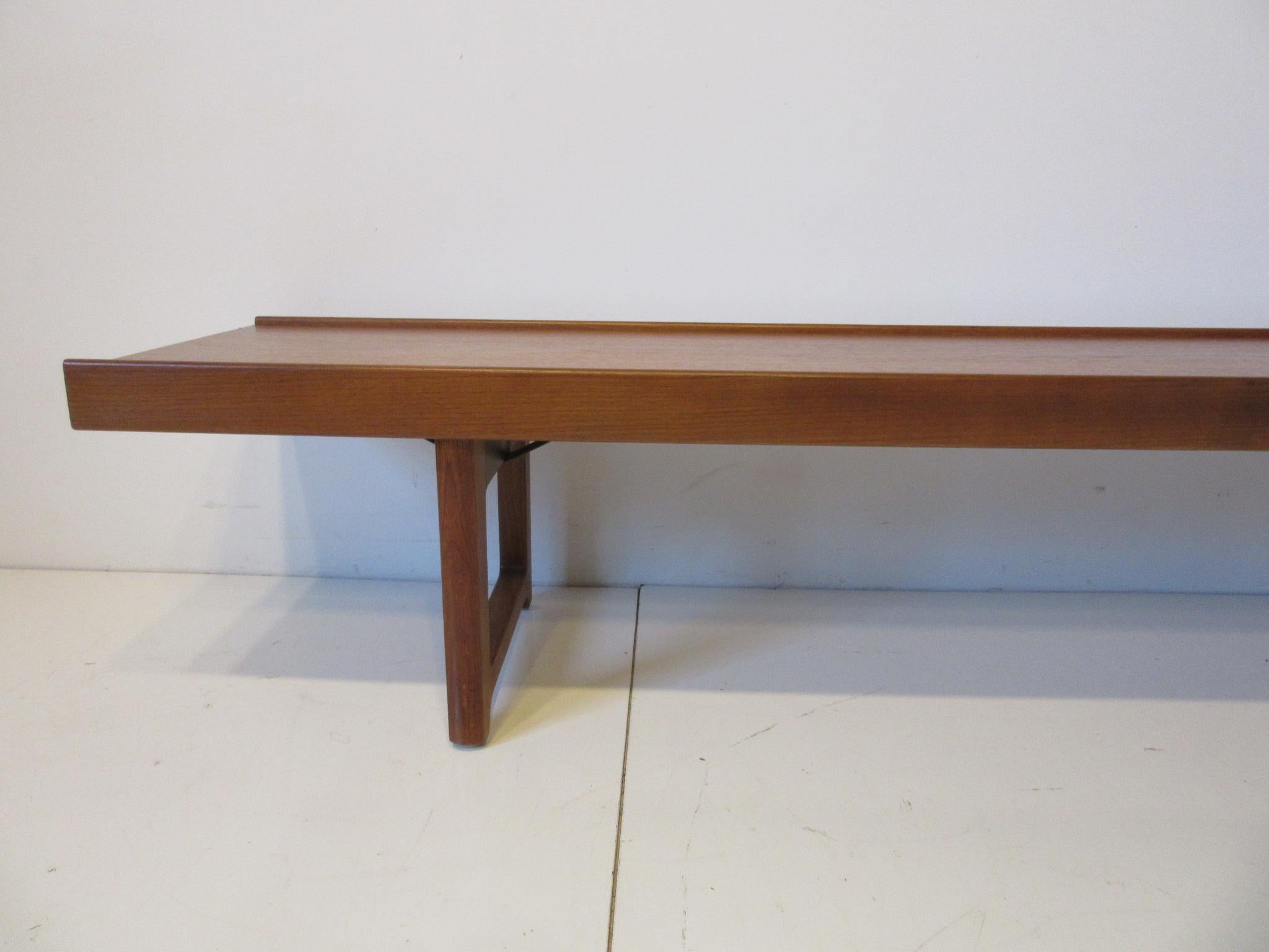 A long solid teak wood Krobo bench with lip to both front and back edges sturdy legs with lower supports this very well crafted bench is perfect for that entrance way or large window area when you need extra seating or just a stylish piece of