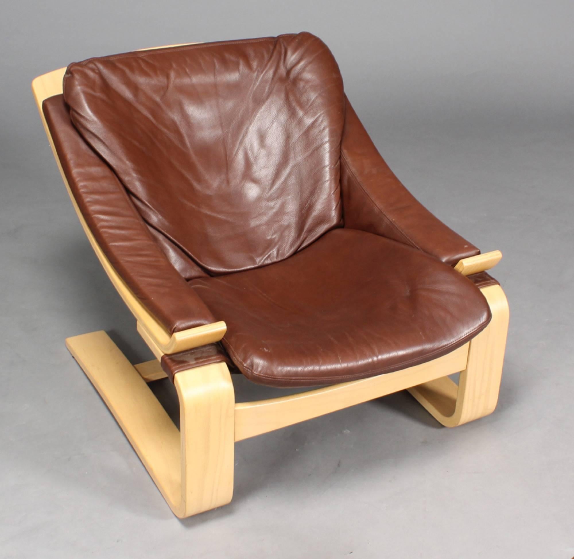 Åke Fribytter, 'Kroken' armchair and a stool with a frame of shaped beech wood upholstered with brown leather. Designed in 1974. Produced by Nelo, Sweden, with the 25th anniversary plaque, the number limited edition No. 257/1000.