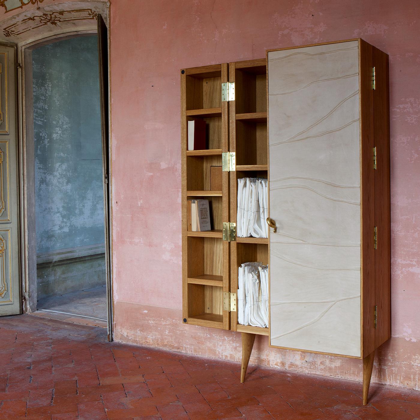 This bookcase by NB Milano is a harmonious composition of wood and leather. The poplar and okoume plywood structure is veneered in polished oak, finished and polished with beeswax and linseed oil. Frontally, the bookcase is covered with full grain