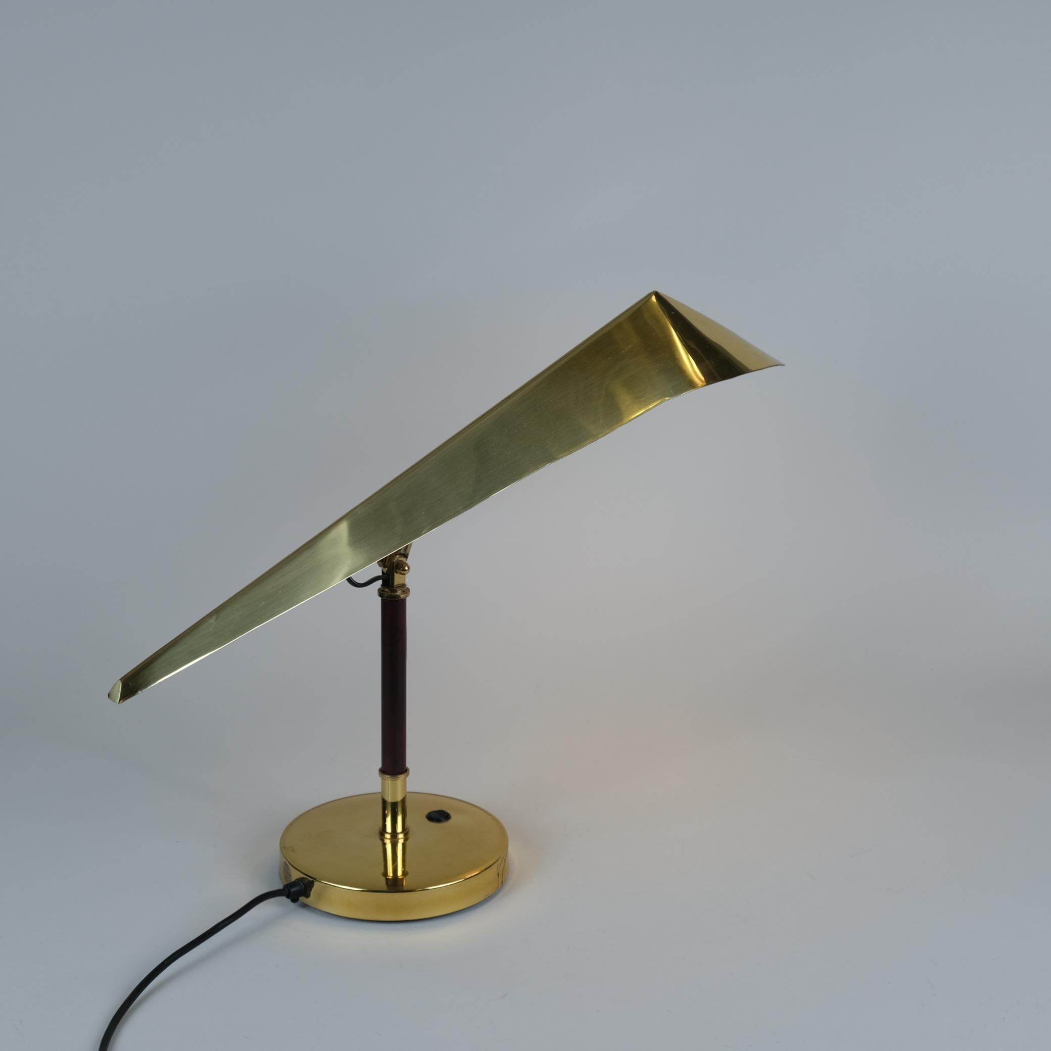 A beautiful and distinct Finnish design table lamp manufactured by Kone- Tukku Valaistus Oy in Finland in the late mid 20th century. The lamp features a very distinct spear shaped brass shade combined with a beautiful teak wood base. The materials