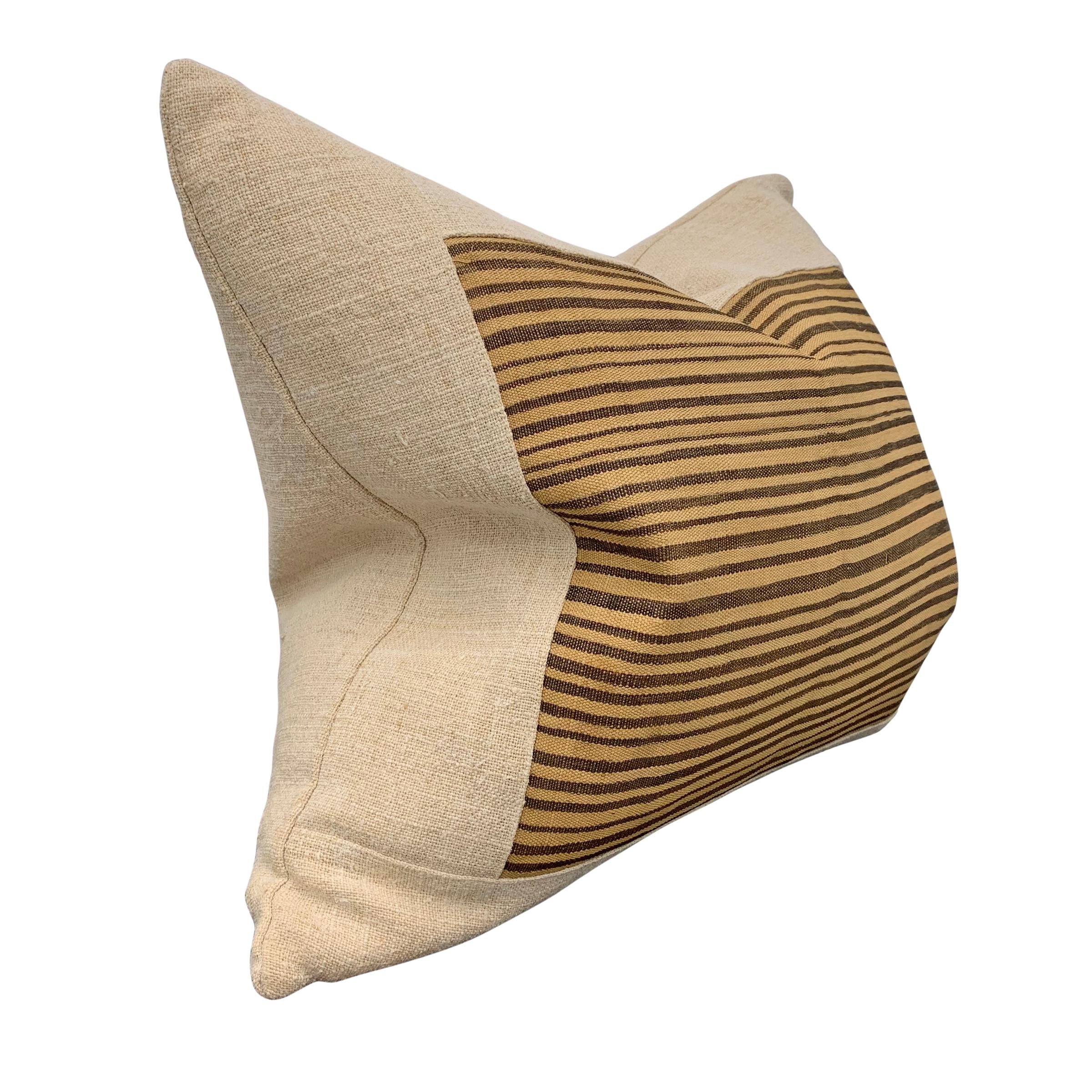 A pillow made from a mid-20th century Kuba cloth, backed with linen and filled with down. Kuba cloth is a raffia fabric woven from thin strips of palm leaf fibers, woven by Kuba women of the Democratic Republic of the Congo into ceremonial skirts