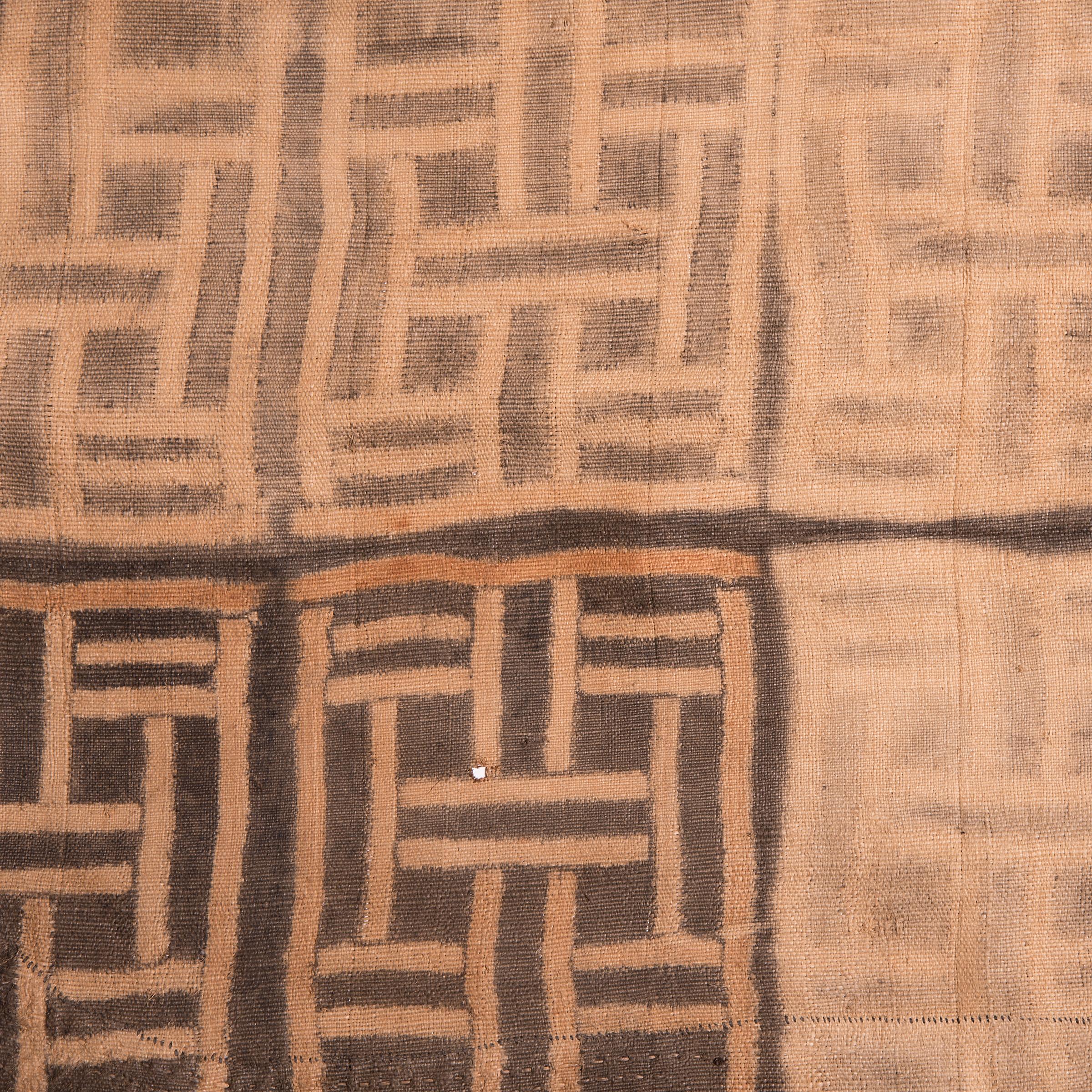 Visually dynamic and highly textured, this raffia textile expresses the irregular, geometric patterns typical of Kuba textile art. Created by an artisan of the Kuba people of the Democratic Republic of the Congo, this textile form is a wrapped