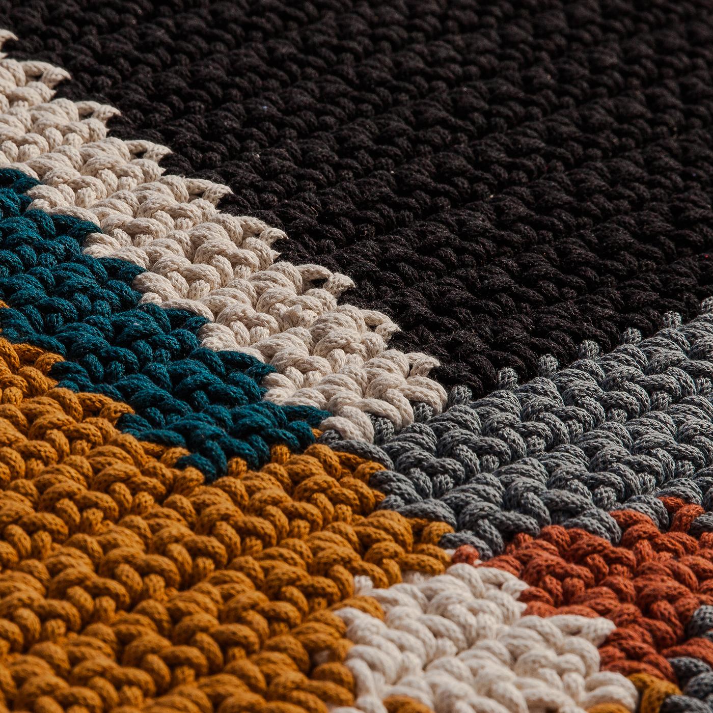 Dieser Teppich ist ein großartiges Beispiel für Handwerkskunst, das moderne Ästhetik mit Nachhaltigkeit verbindet. Er wird aus natürlichem und recyceltem Baumwollgewebe handgehäkelt, ohne künstliche Farbstoffe zu verwenden. Mit seinem ikonischen,