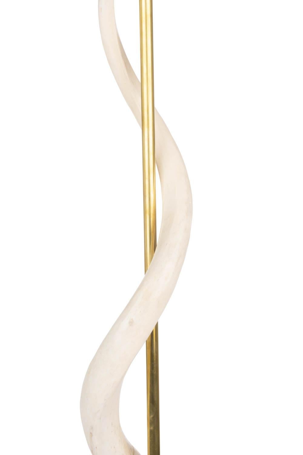 Handcrafted in South Africa, this naturally elegant floor lamp features two inverse African kudu horns encirling a brass rod above a round wooden base, which is wrapped in top-stitched devore cream cow hide with metallic gold accents. All hide and