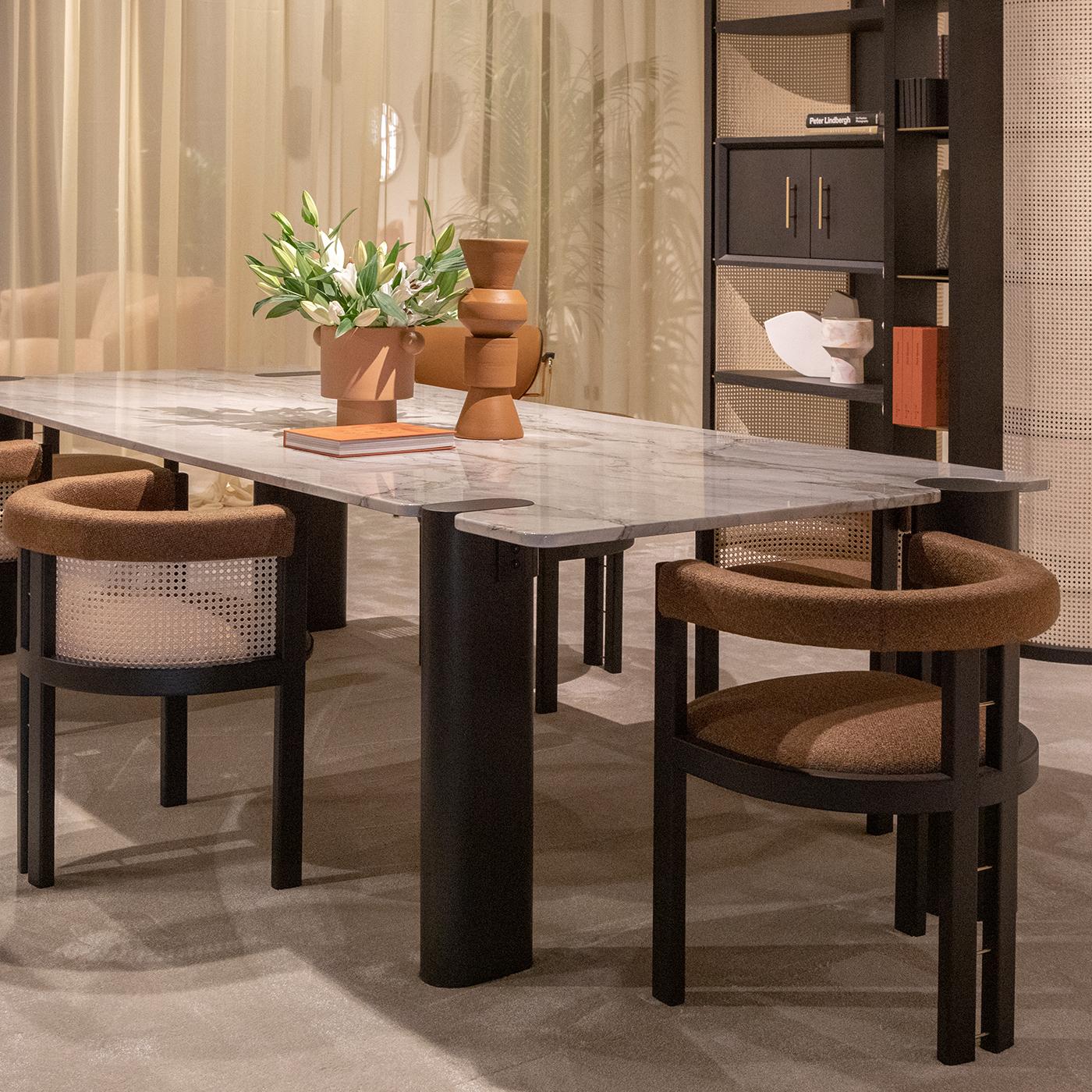 A compact modern throne where to sit for enjoying dinner with friends, this chair boasts a solid construction rich in enveloping curves cleverly counterbalanced by streamlined profiles. Brass rods enrich the solid moka-stained ash frame, which is