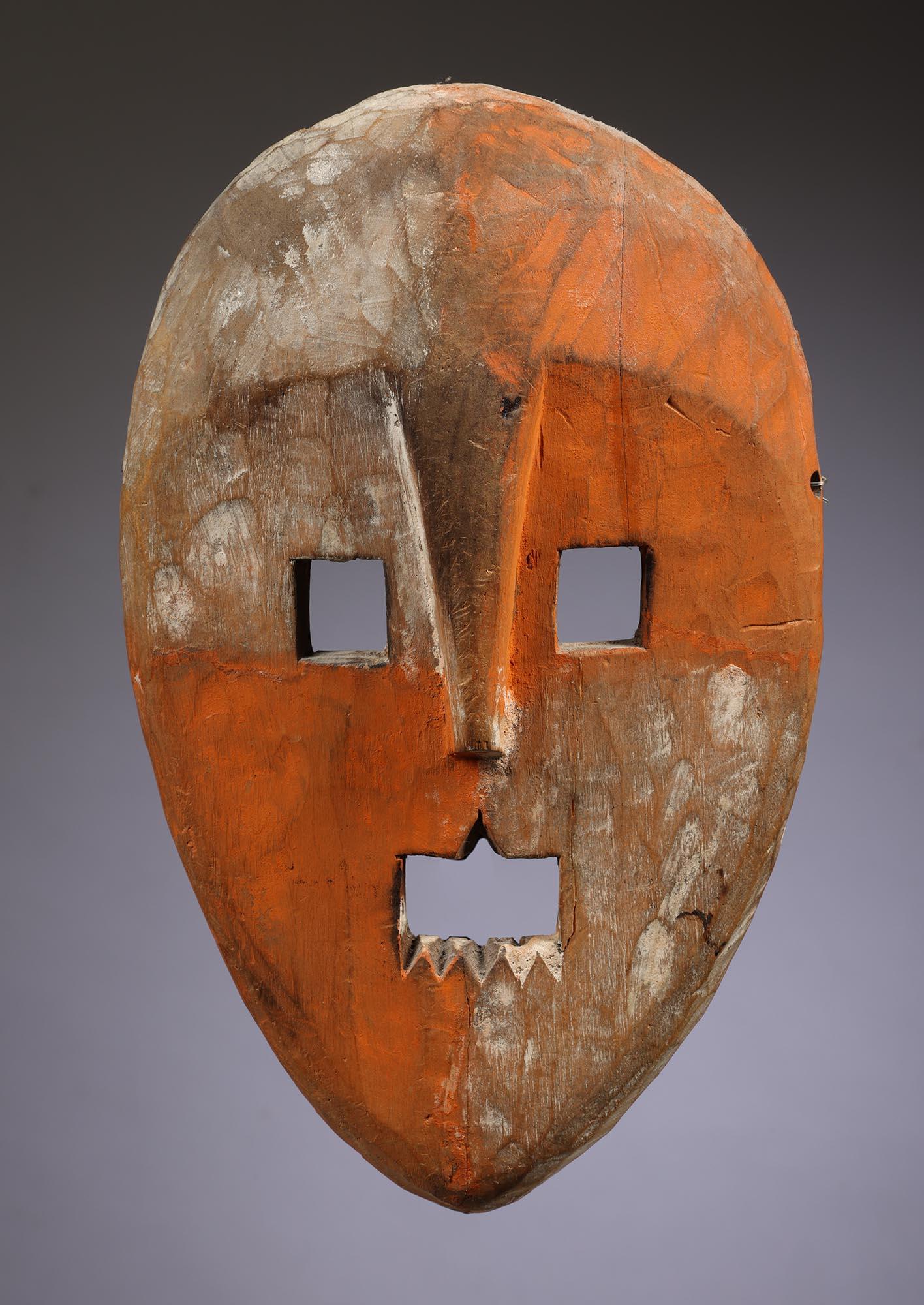 Maschera danzante in legno chiaro dell'inizio o della metà del secolo, proveniente dalla regione di Kumu o Maniema, Repubblica Democratica del Congo, Africa, con il volto diviso in quattro quadranti opposti con pigmenti arancioni e tracce di bianco.