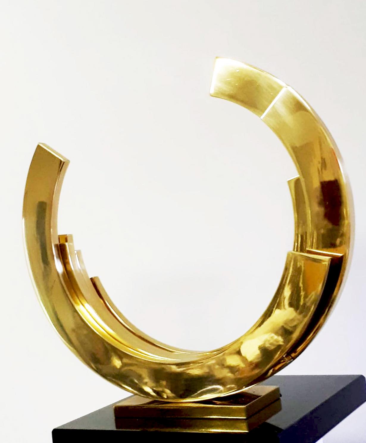 Beautiful golden circular sphere by artist Kuno Vollet., This contemporary abstract sculpture is an elegant piece. The brass has been coated to help reduce stains on the precious metal. 
The size of the sculpture is 36 x 36 x 8 cm. 

The gold makes