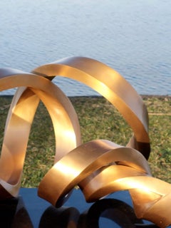 Infinitum Big de Kuno Vollet - Escultura de bronce pulido dorado sobre base de granito