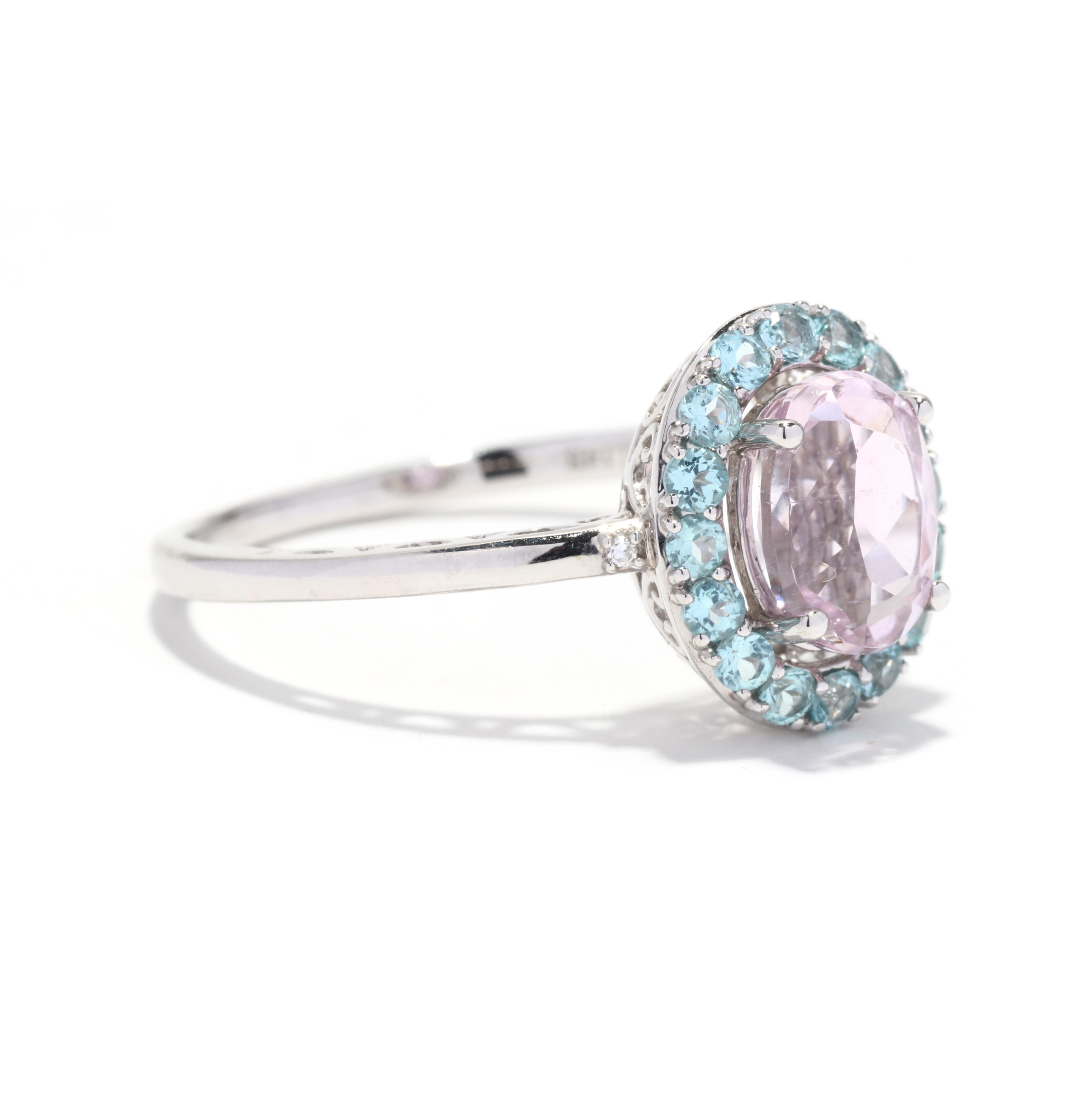 A vintage 14 karat white gold kunzite and aquamarine ring. This simple ring features a prong set, oval cut kunzite center stone weighing approximately 2.03 carats surrounded by a halo of round cut aquamarines weighing approximately .64 total carats