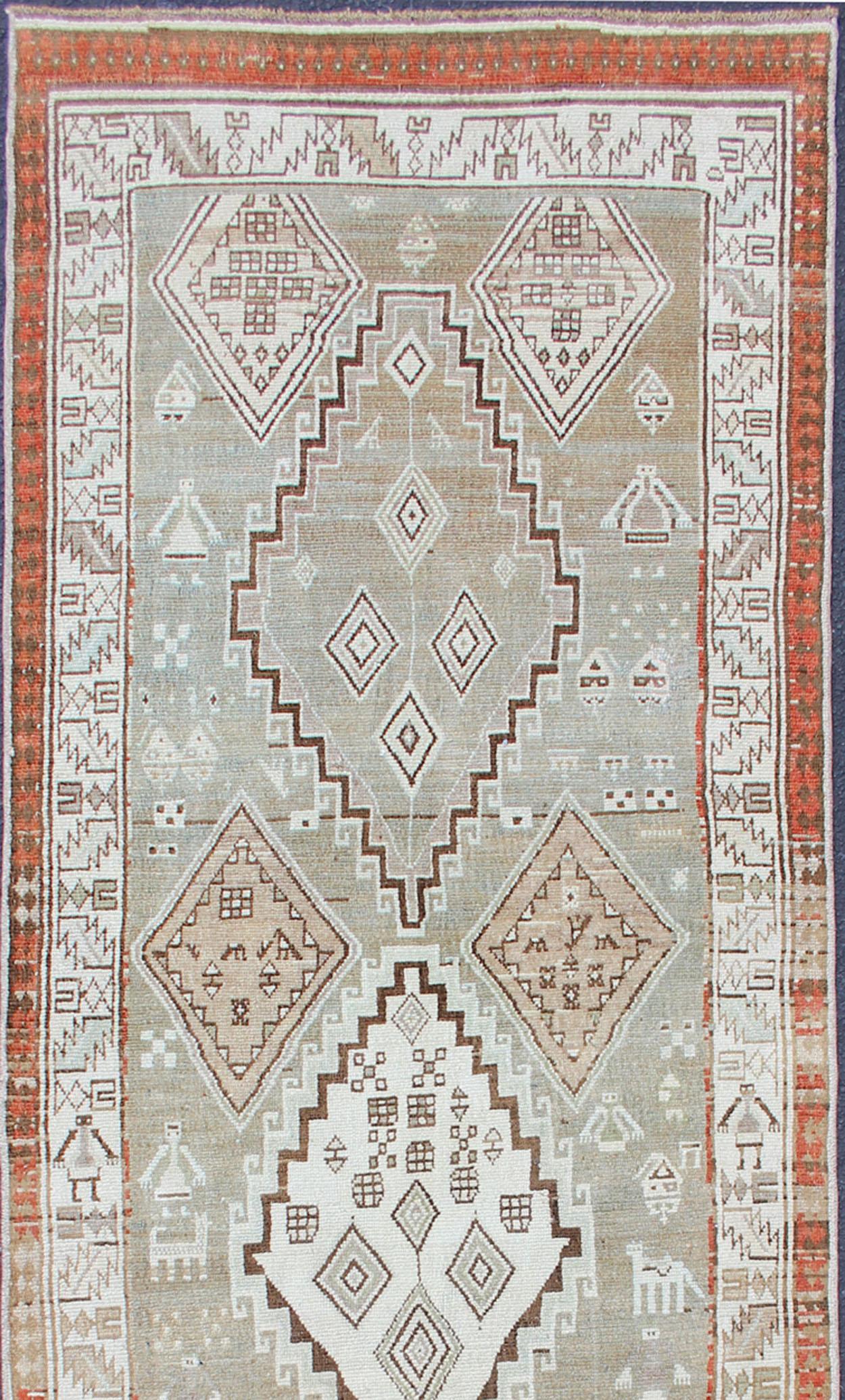 Antique Kurdish runner antique with tribal geometric medallions in soft green, brown, tape, salmon and orange-red border. rug SUS-2009-553, country of origin / type: Iran / Kurdish, circa 1900.
This Kurdish runner from early 20th century Persia is