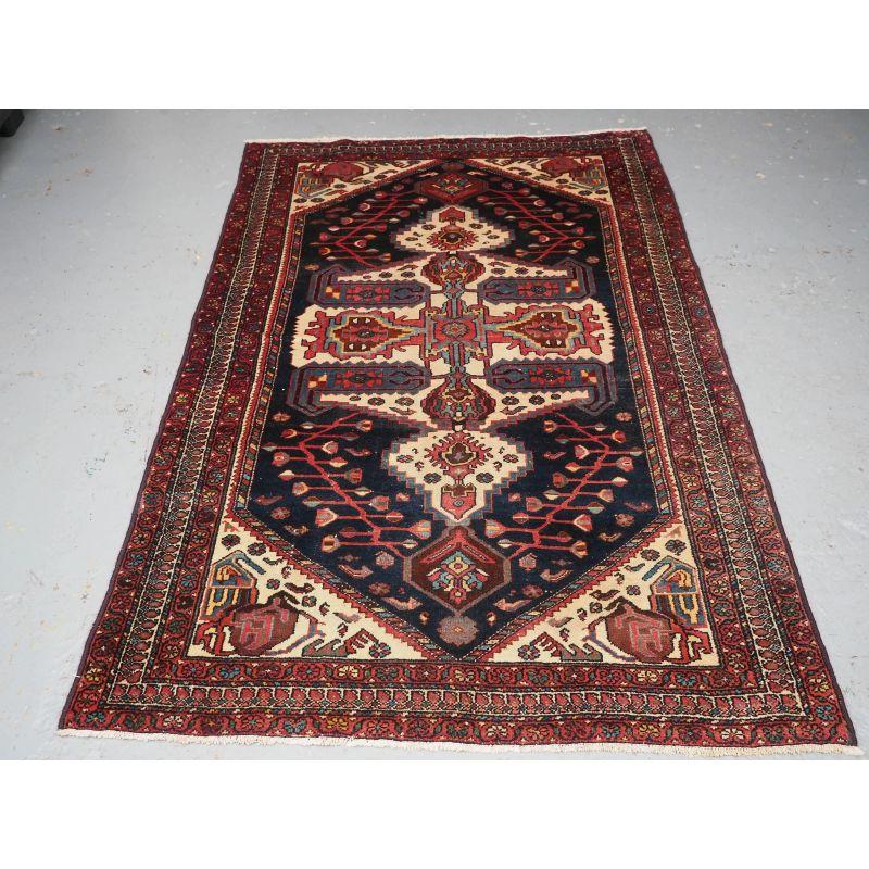 A good Kurdish village rug from the Greater Hamadan Region.

The rug has a large central hooked medallion. The ivory stands out against the dark indigo blue ground, the medallion is surrounded by a floral vine.

The rug is in good condition with