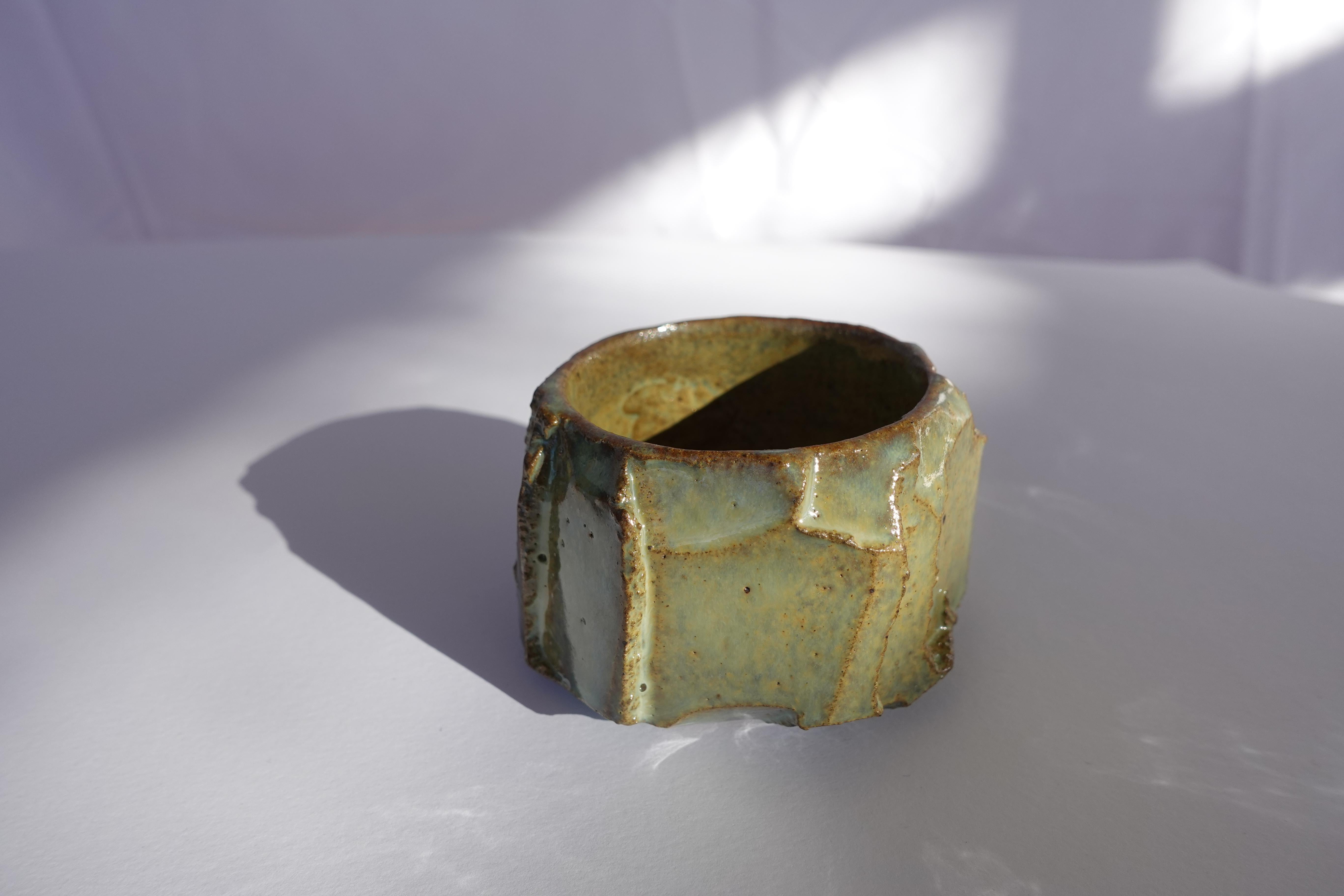 Cette tasse à expresso a d'abord été tournée au tour, puis méticuleusement sculptée à la main selon la technique traditionnelle du kurinuki, permettant à la forme d'émerger intuitivement de l'argile. Chaque angle, arête et surface texturée révèle un