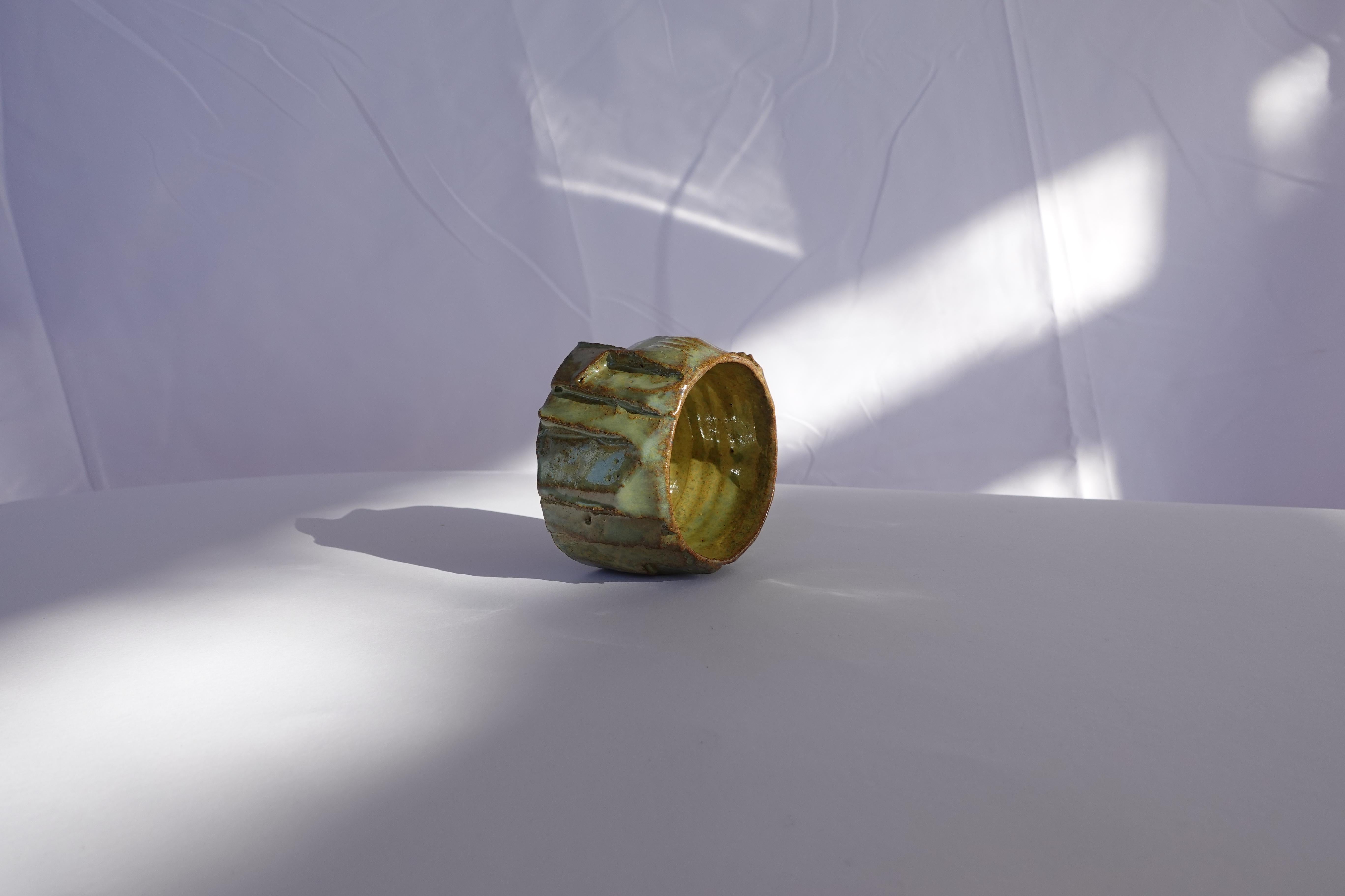 Cette tasse à expresso a d'abord été tournée au tour, puis méticuleusement sculptée à la main selon la technique traditionnelle du kurinuki, permettant à la forme d'émerger intuitivement de l'argile. Chaque angle, arête et surface texturée révèle un