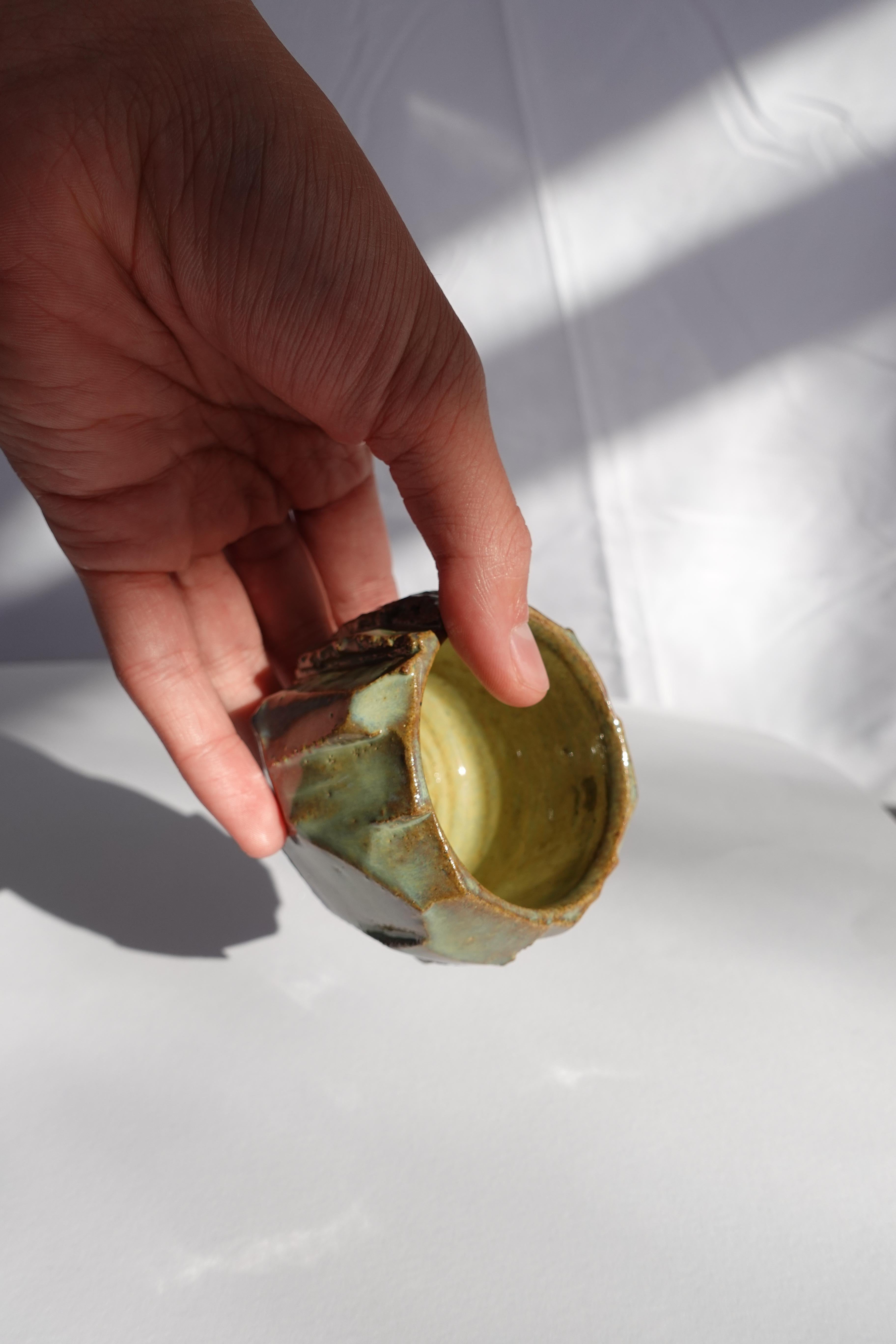 Cette tasse à expresso a d'abord été tournée au tour, puis méticuleusement sculptée à la main selon la technique traditionnelle du kurinuki, permettant à la forme d'émerger intuitivement de l'argile. Chaque angle, arête et surface texturée révèle un