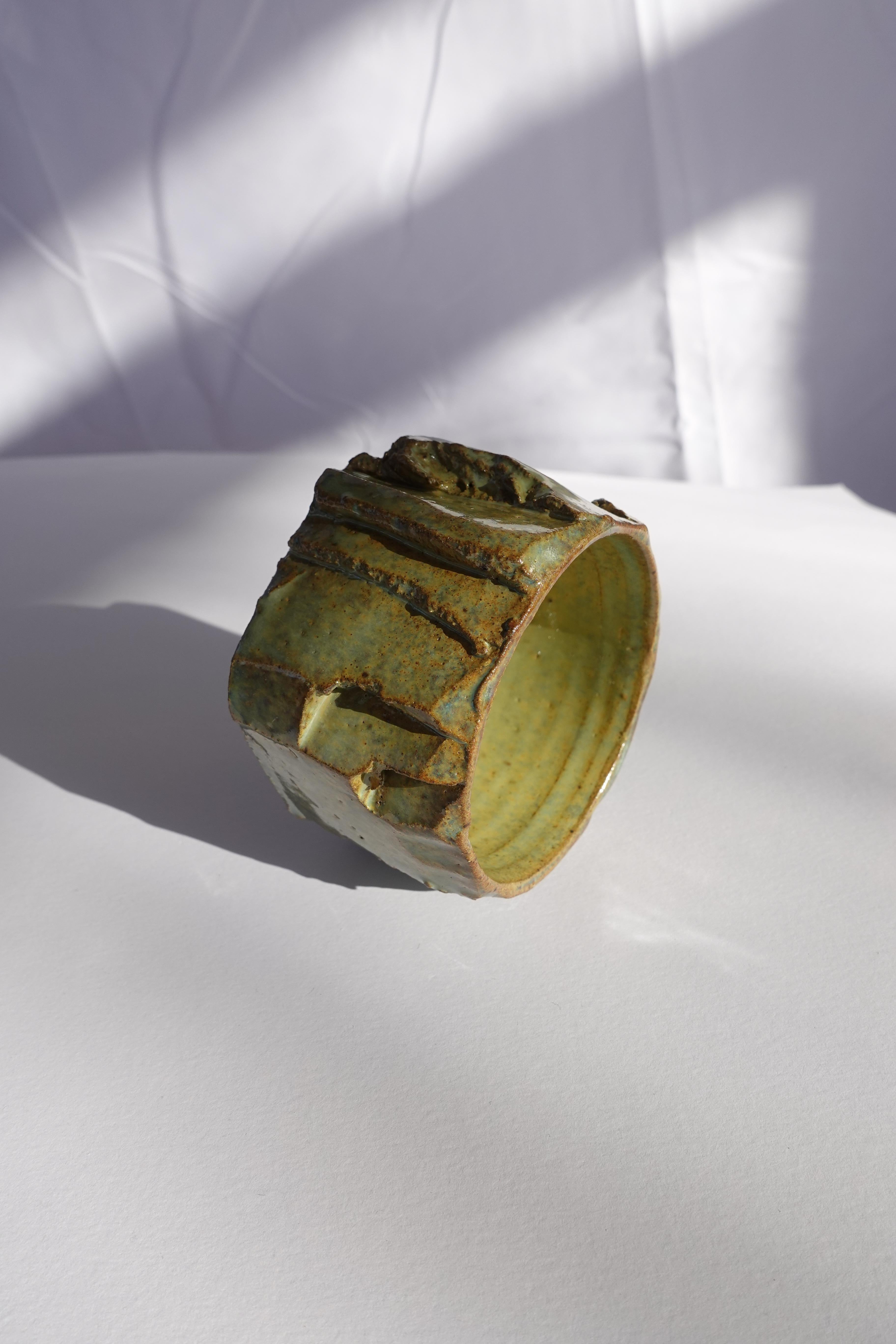 Cette tasse à expresso a d'abord été tournée au tour, puis méticuleusement sculptée à la main selon la technique traditionnelle du kurinuki, permettant à la forme d'émerger intuitivement de l'argile. Chaque angle, arête et surface texturée révèle un