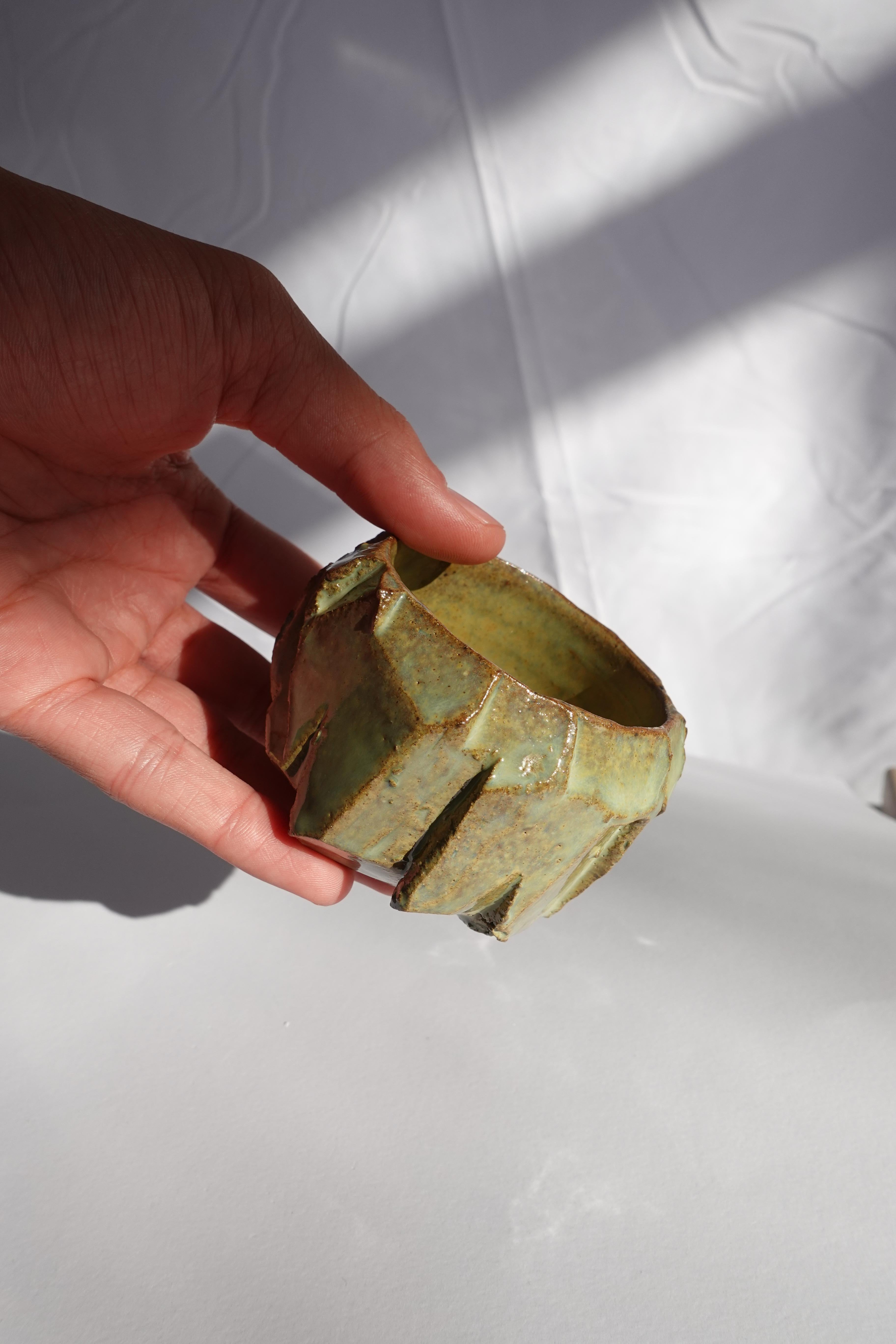 Cette tasse à expresso a d'abord été tournée au tour, puis méticuleusement sculptée à la main selon la technique traditionnelle du kurinuki, permettant à la forme d'émerger intuitivement de l'argile. Chaque angle, arête et surface texturée révèle un