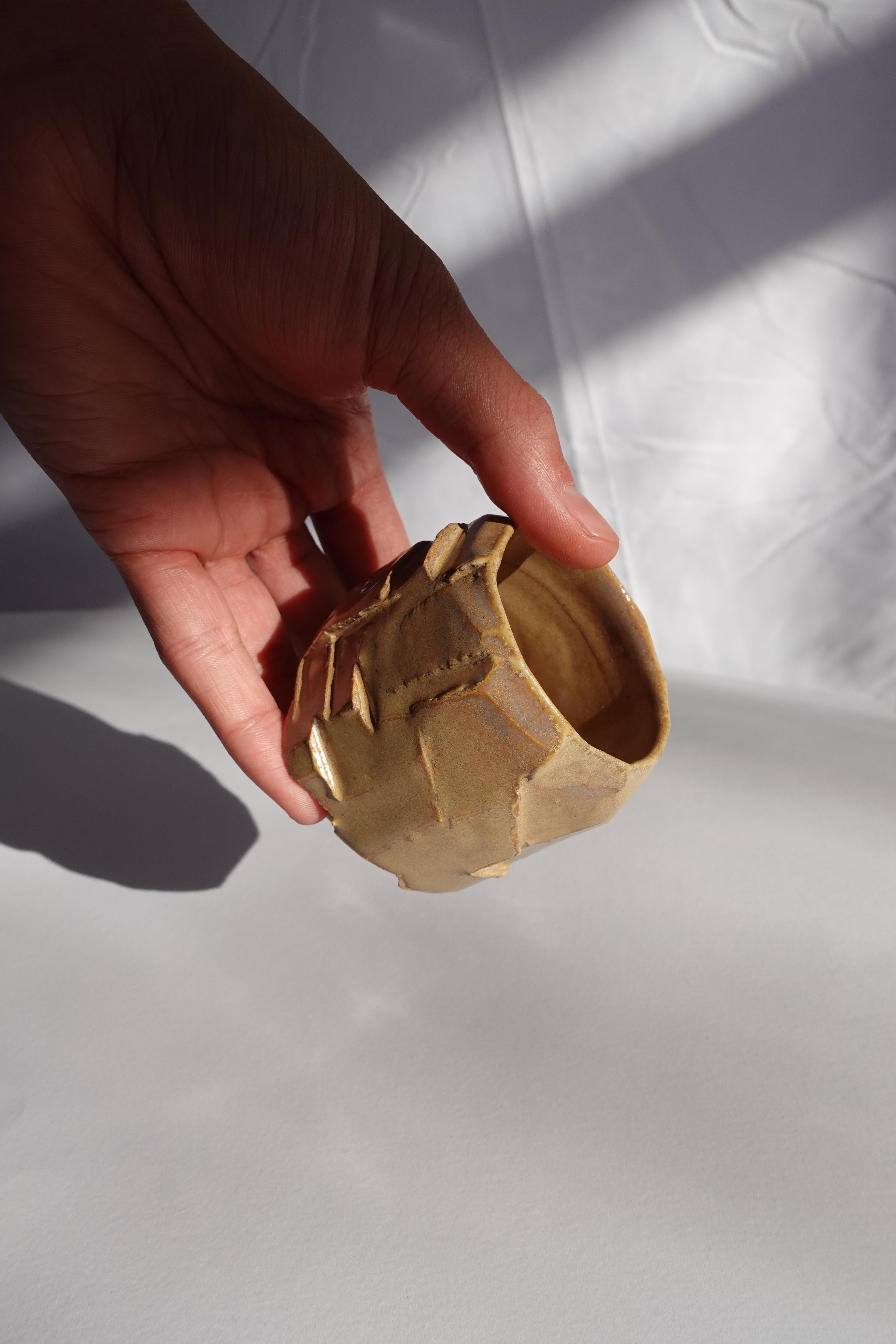 Cette tasse à expresso a d'abord été tournée au tour, puis méticuleusement sculptée à la main selon la technique traditionnelle du kurinuki, permettant à la forme d'émerger intuitivement de l'argile. Chaque angle, arête et surface texturée révèle un