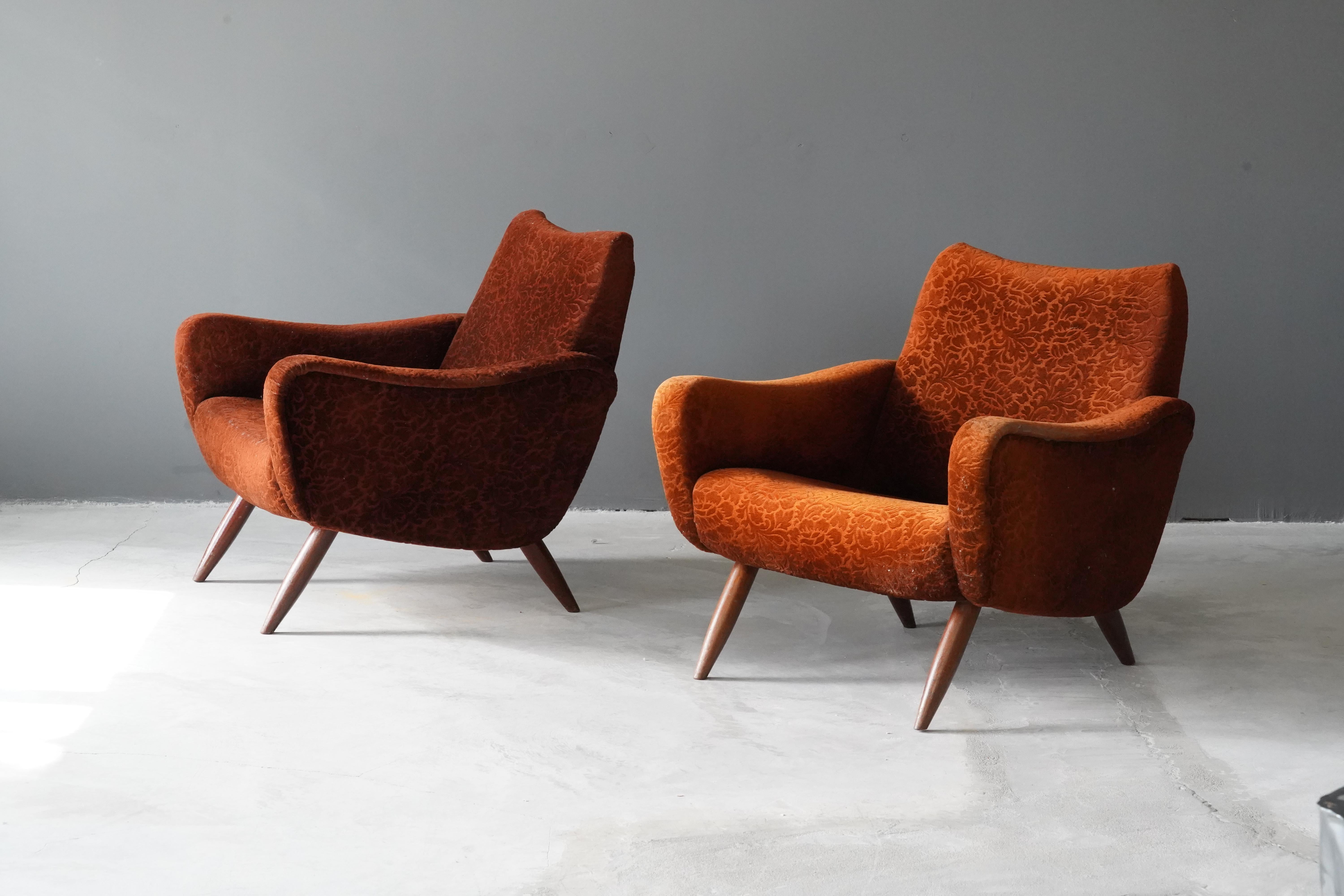 A pair of freeform lounge chairs / armchairs, designed by Kurt Hvitsjö for Isku, Finland, 1950s.

Features an overstuffed wooden structure on finely turned wooden legs. 

Other designers of the period include Gio Ponti, Alvar Aalto, Carlo