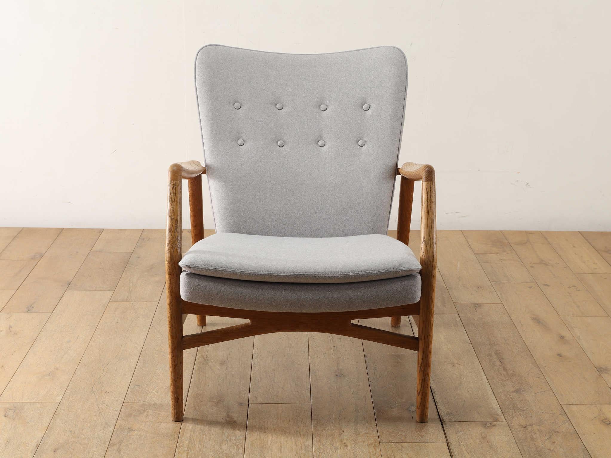 Elegante sillón modelo 215 con una forma muy vanguardista diseñado por el danés Kurt Olsen en los años 50, que combina el roble macizo rugoso de grano grueso con un respaldo y un asiento estables. El respaldo y el asiento estables son de la mejor