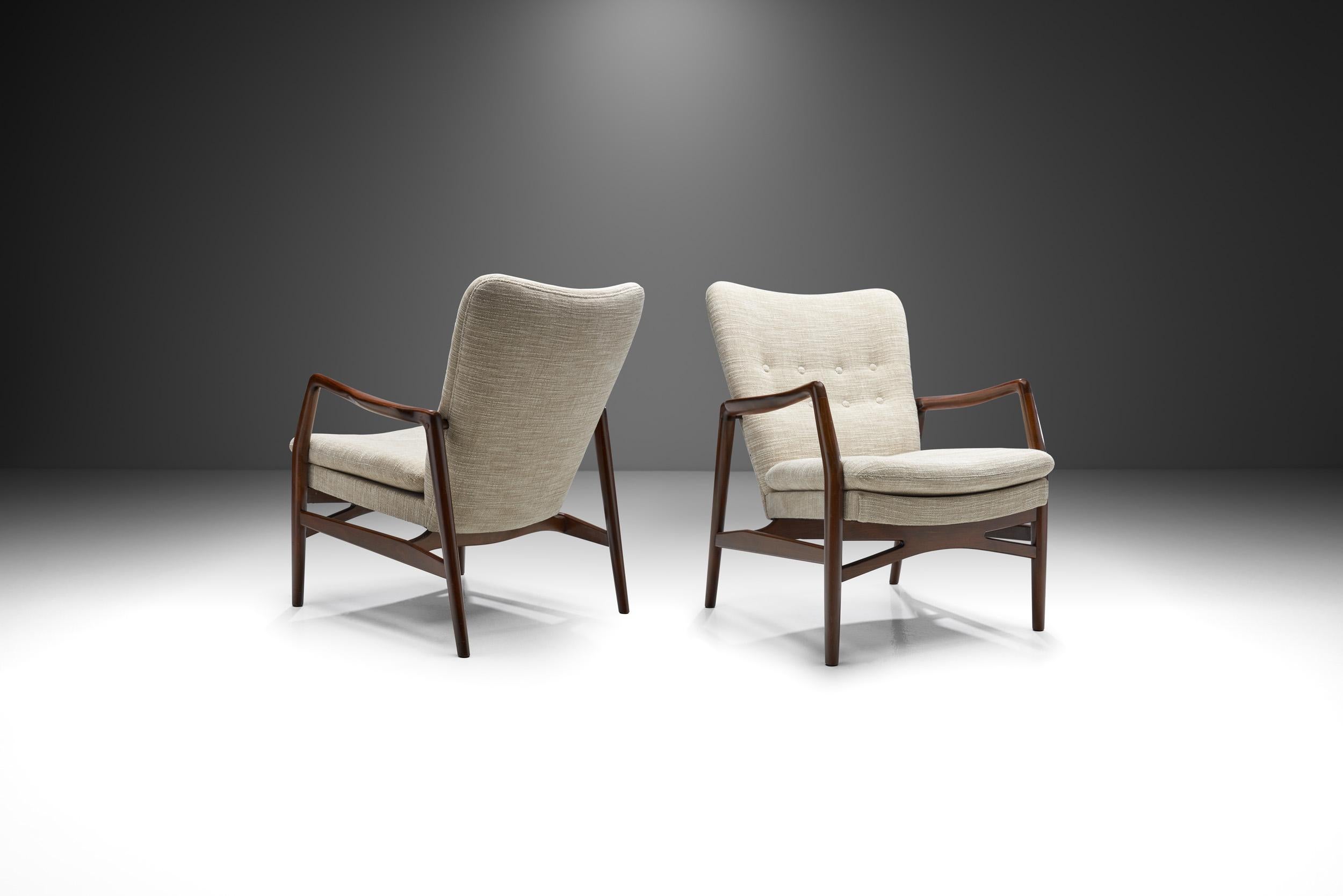 This pair of “Model 215” easy chairs were designed by Danish designer and architect Kurt Olsen, and unifies some of the best characteristics of mid-century Danish design and craftsmanship.

The elegantly modern and precise design of these chairs is