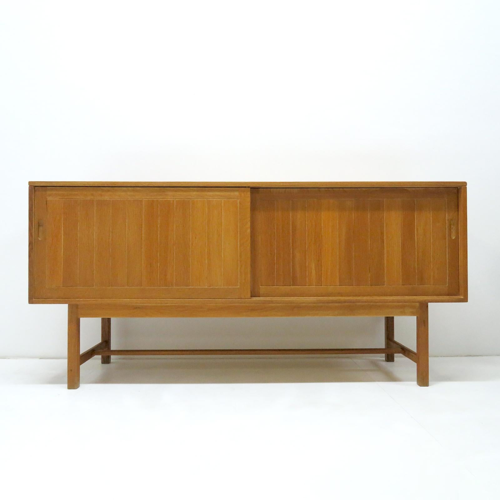 Bold Danish modern, solid oak credenza by Kurt Ostervig for KP Möbler, 1960, with two sliding doors, one center shelf behind one door and one center shelf and four felt lined drawers behind the other door, all in sturdy oak in great condition.