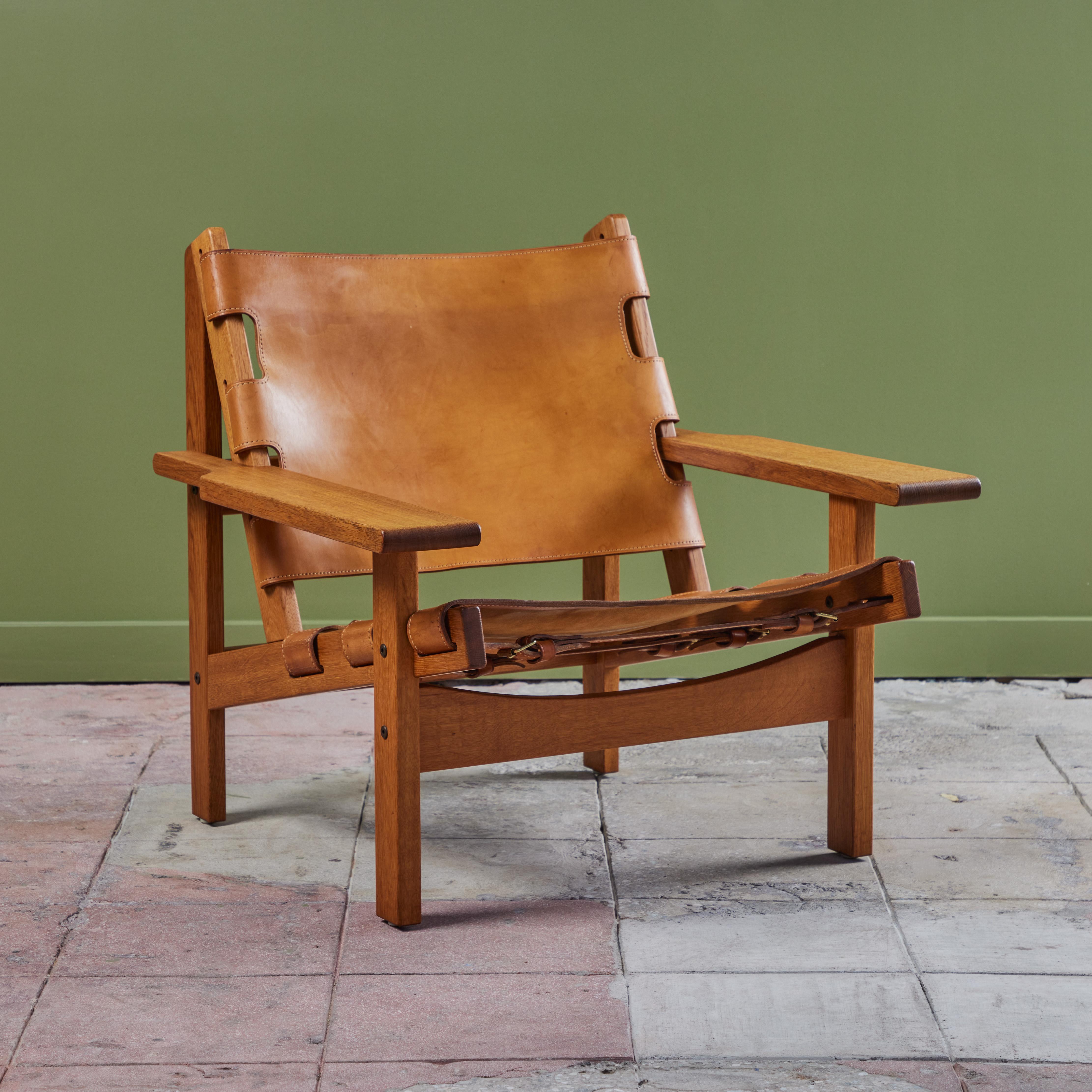 Lounge chair by Kurt Ostervig, c.1960s, Denmark. The low slug lounge chair also referred to as the hunting chair has an oak frame with angular armrests. The aged cognac saddle leather backrest and seat rest are rich with character, consistent with