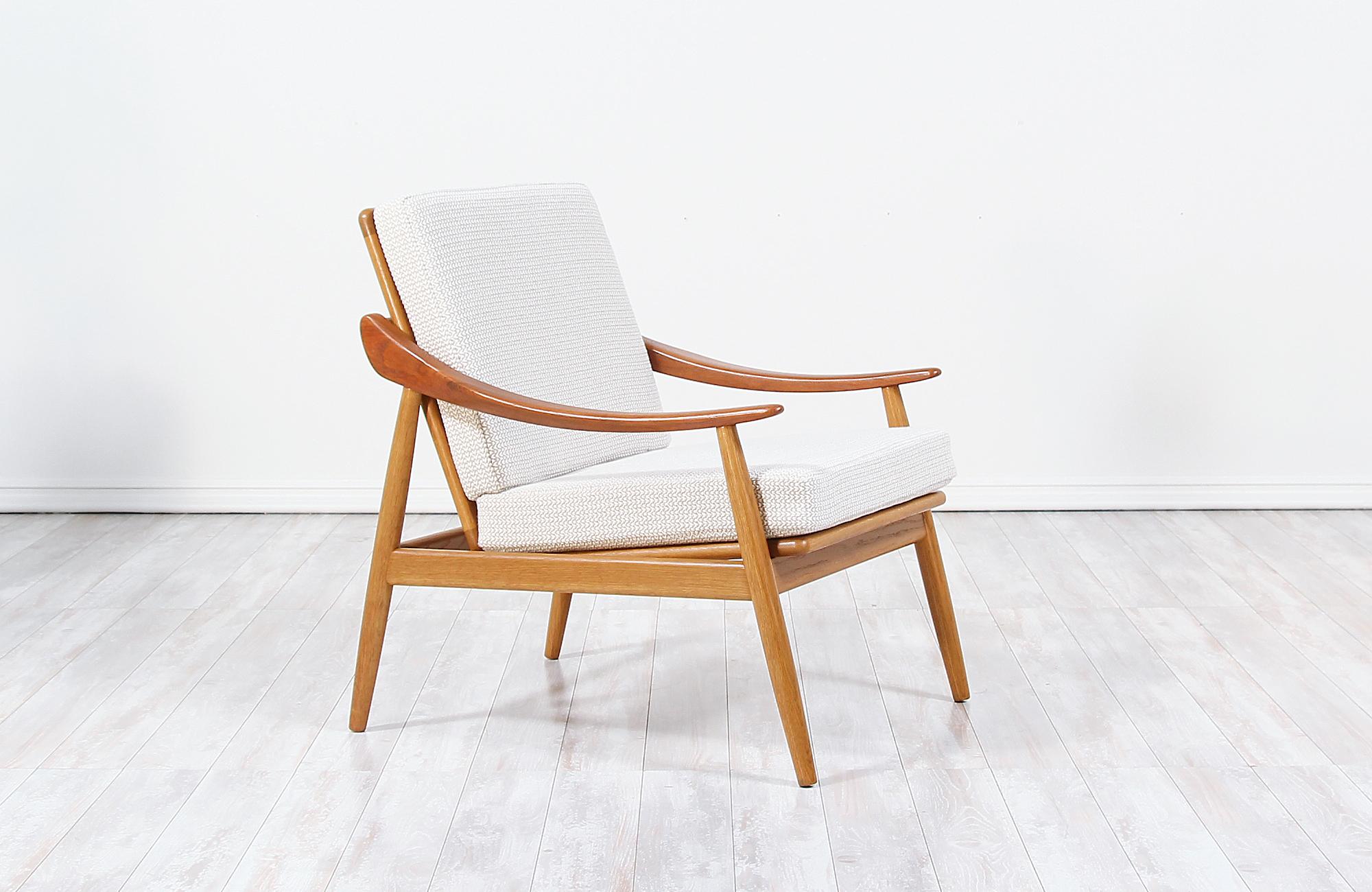 Stylish reclining Danish Modern lounge chair designed by Kurt Østervig for Jason Møbler in Denmark in 1956. This beautiful Model 301 lounge chair features a solid oak wood frame with curved teak wood sculpted armrests balancing the design's symmetry