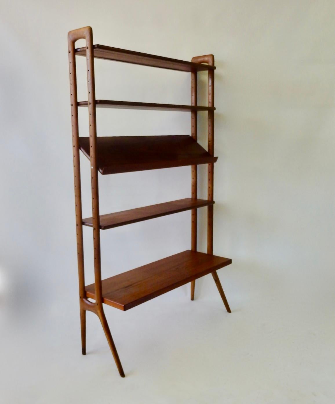 Modular and adjustable Danish teak wood bookshelf or room divider. Designed by Kurt Ostervig crafted by Povl Dinesen. Four shelves plus one angled display shelf. Lower shelf is deeper at 15.75