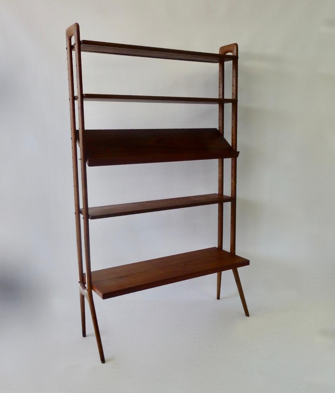 Modular and adjustable Danish teak wood free standing bookshelf or room divider. Designed by Kurt Ostervig crafted by Povl Dinesen. Five shelves one having an angled magazine or book display shelf. Lower shelf is deeper at 15.75