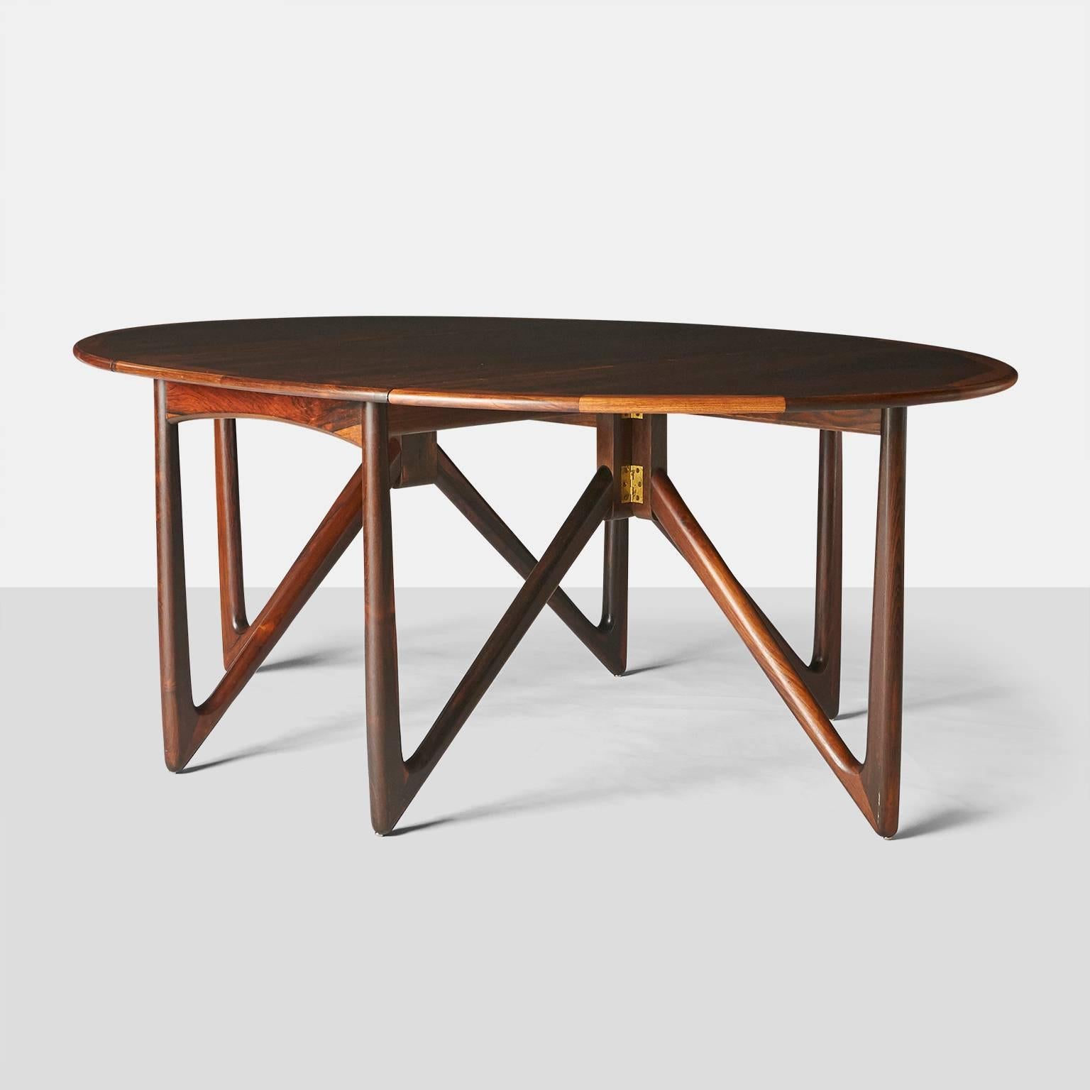 A rosewood dining table designed by Kurt Ostervig. The gatefold legs are of solid rosewood, and the table can change from a compact form to an impressive dining table that will seat eight.