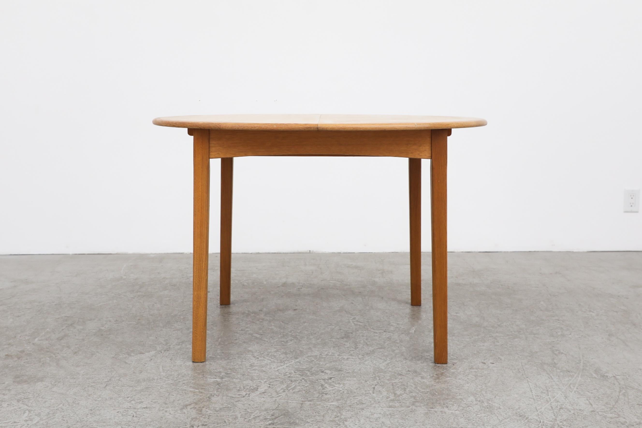 Mid-century dining table by Kurt Østervig. This small round oak table features a hidden extension leaf that sits underneath the table top and folds out in two sections. The leaf measures 13.87
