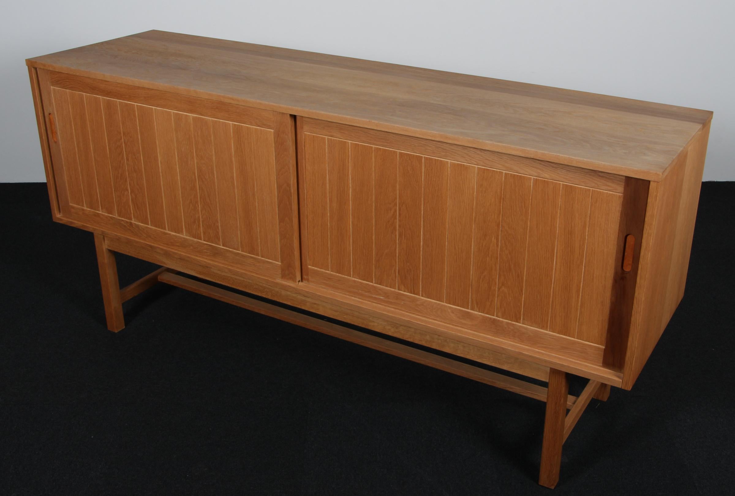 Kurt Østervig cabinet in partly solid oak. 

With sliding doors and drawers.

Made by KP Møbler.