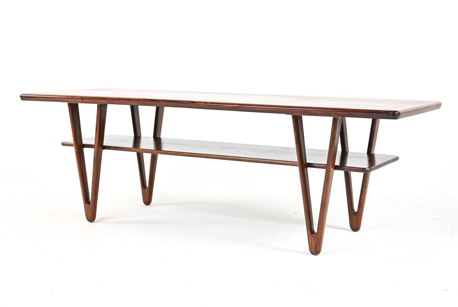 Balanced on delicate sculpted hairpin legs, this two-tier rosewood coffee table by Kurt Østervig is a feat of superior craftsmanship and design.