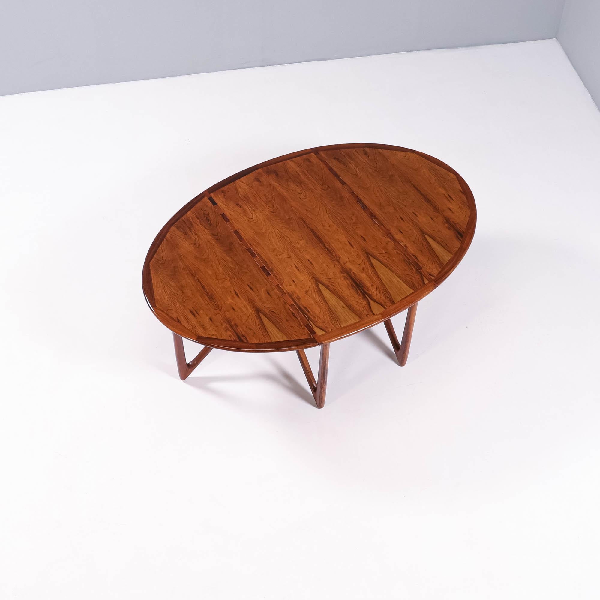 This rare drop-leaf dining table in rosewood shows an unusual, impressive base of six V-shaped legs, made with extraordinary craftsmanship and designed by Kurt Østervig for Jason Furniture in Denmark. 

The legs on both ends can be turned, which